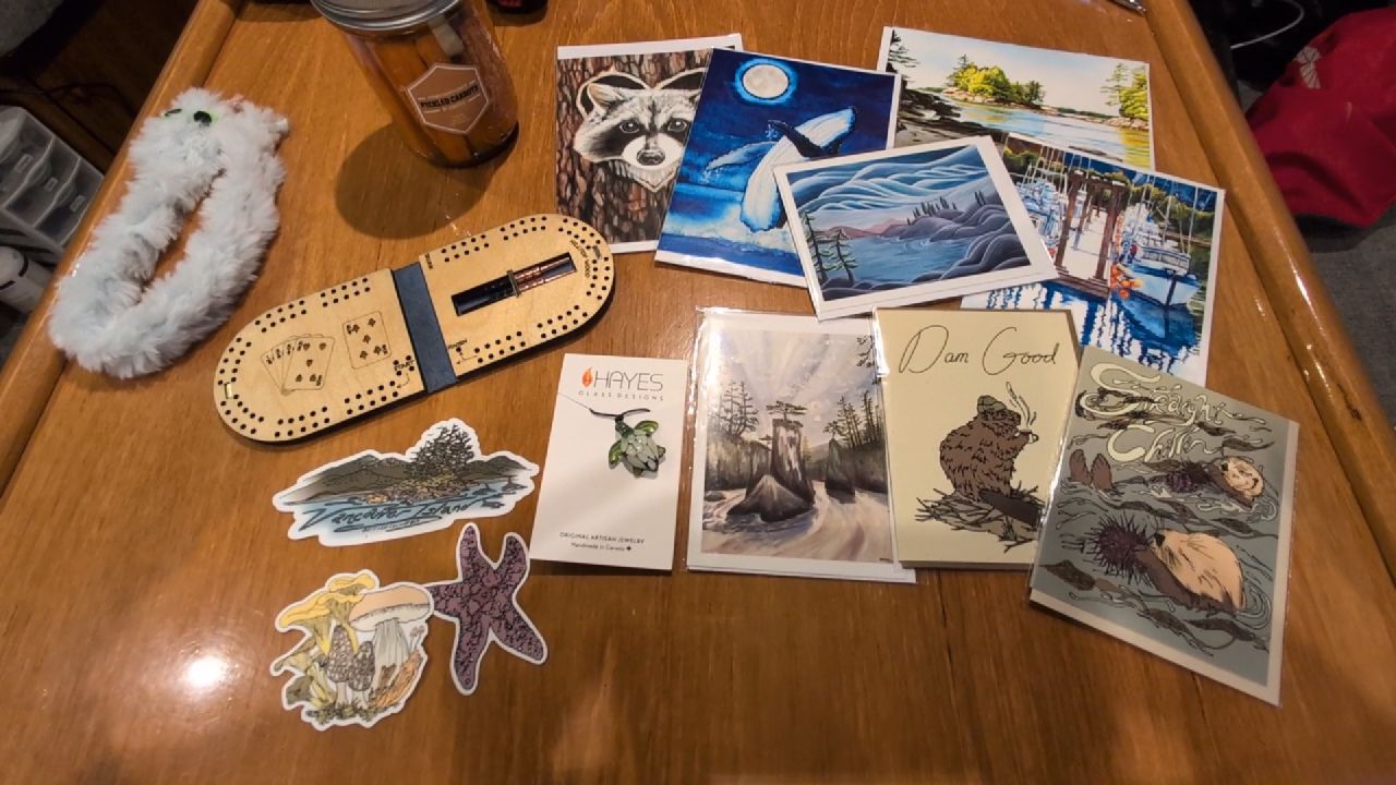 Souvenirs from the Nanaimo arts walk including a mini cribbage board, local art prints, and stickers