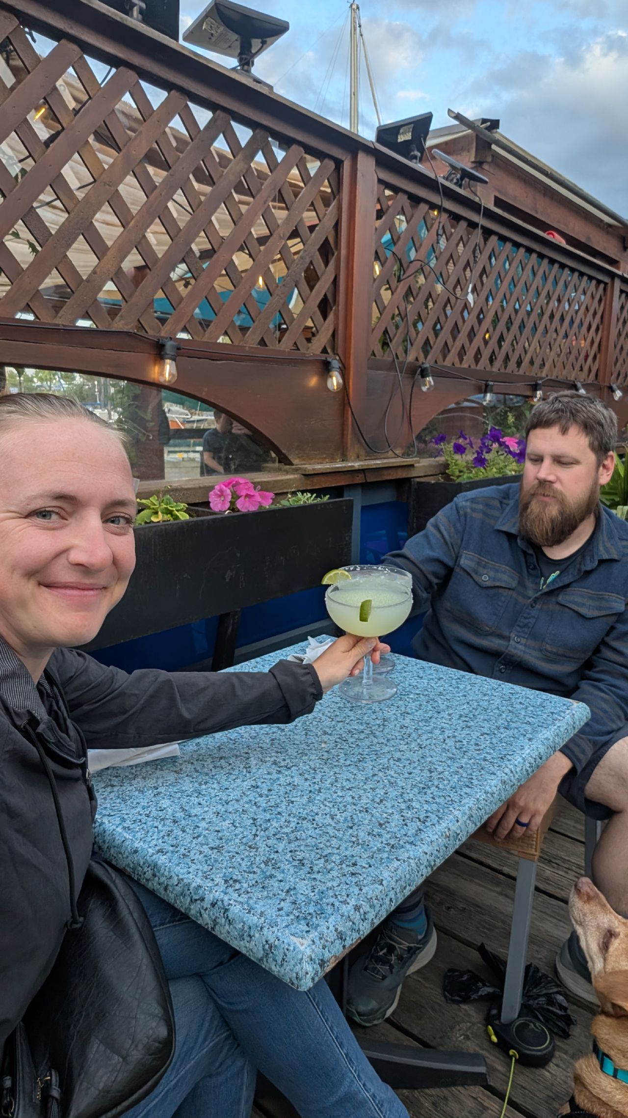 Rachel holding a margarita with Brian and Maui at a floating restaurant in Nanaimo