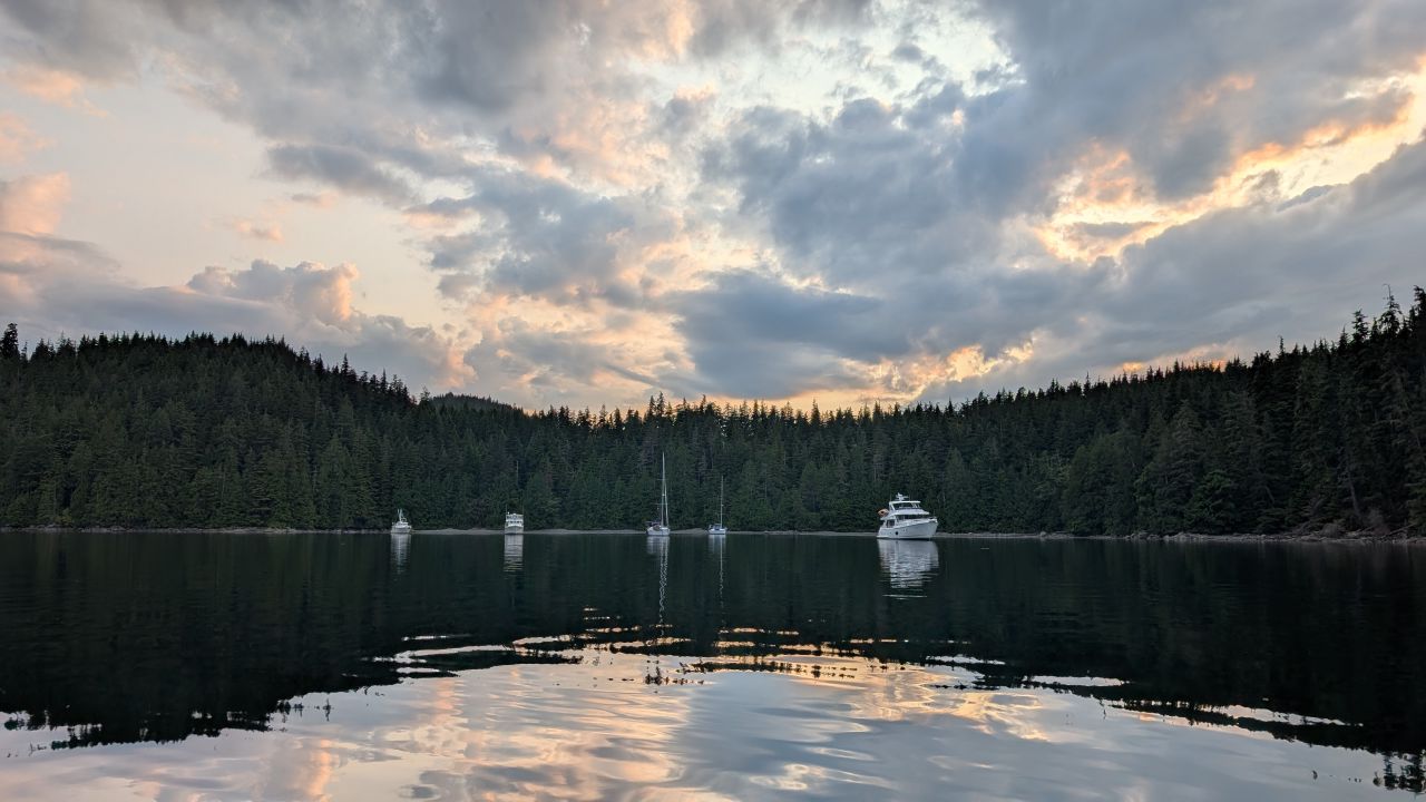 Boats anchored at sunset in Forward Harbour with evergreen forest reflections on glassy water