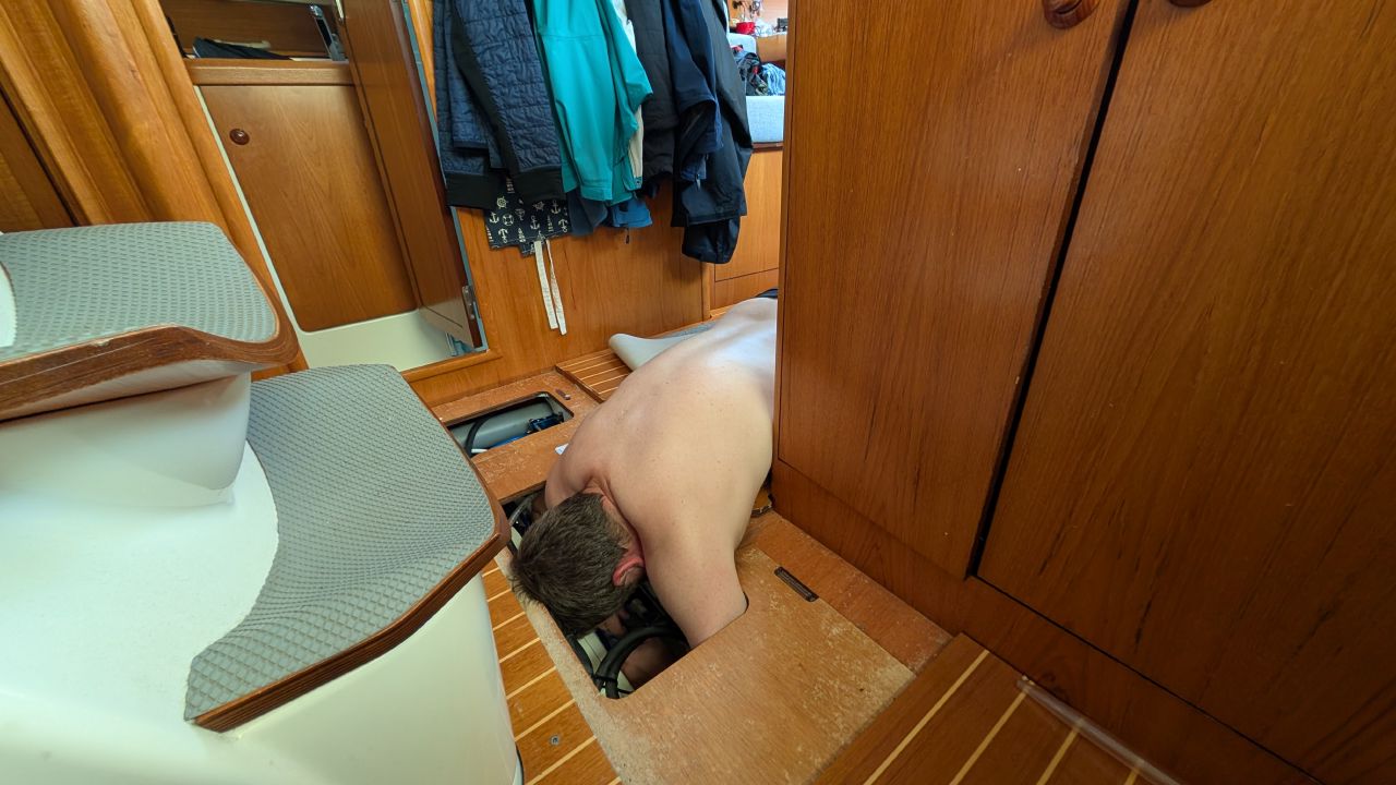Brian working below deck in the bilge repairing the watermaker aboard SV Yahara