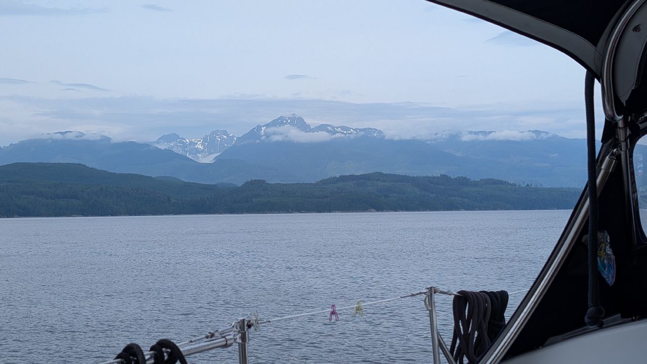 Snow-capped mountains seen from behind the dodger while sailing Johnstone Strait