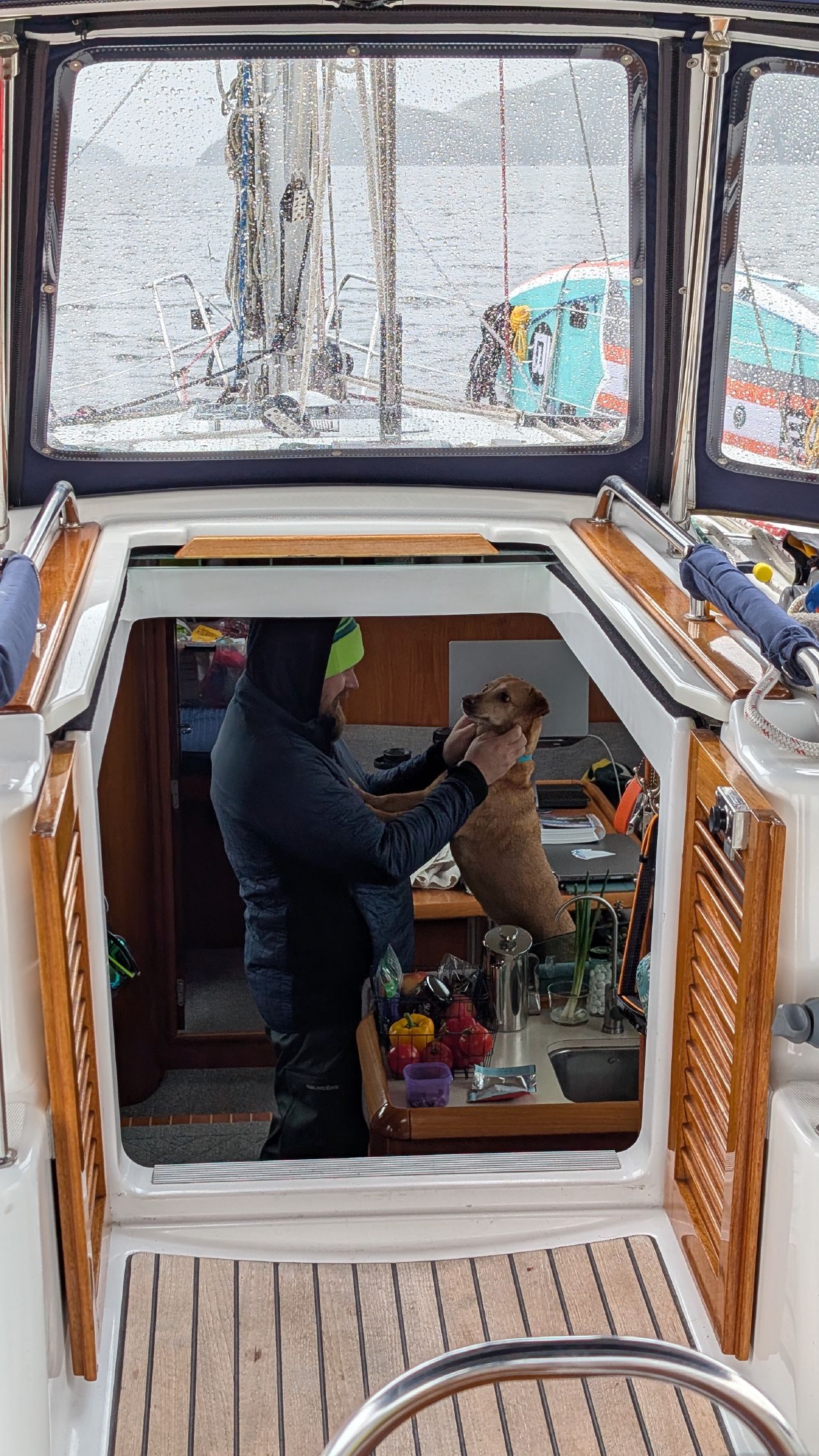 Brian petting Maui in the companionway of SV Yahara on a rainy day
