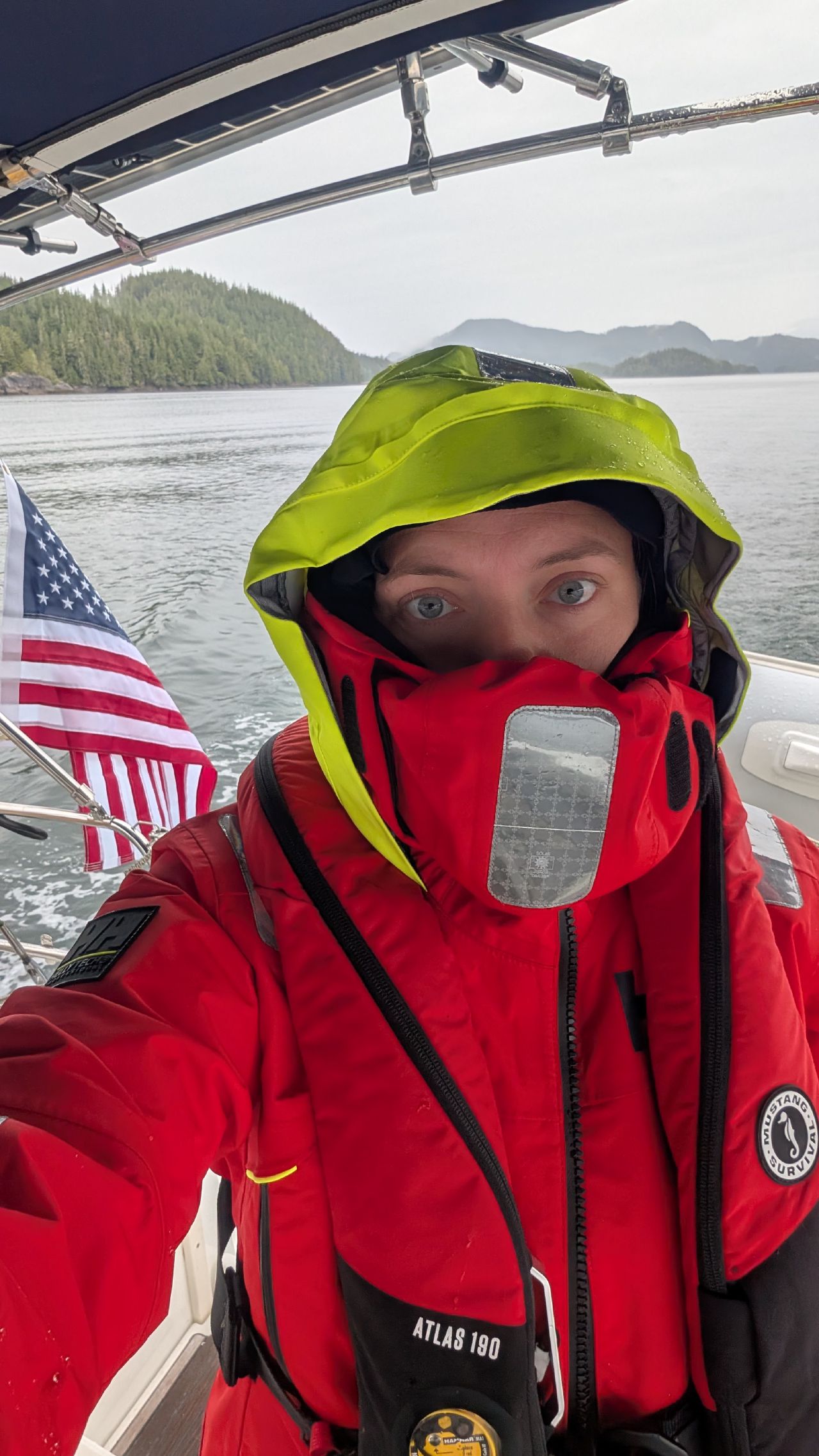 Rachel bundled up in red foul weather gear selfie during a cold rainy passage