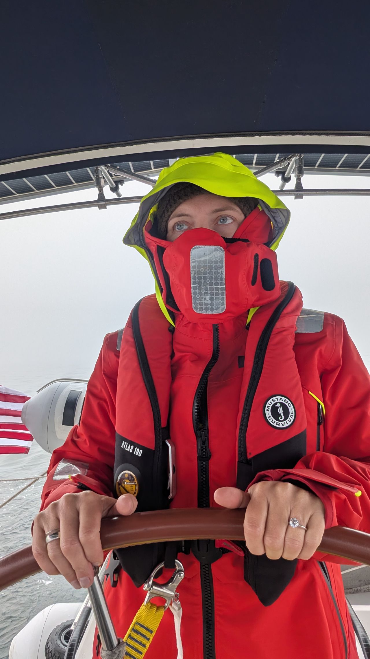 Rachel gripping the helm in full Mustang survival suit during the Cape Caution offshore crossing