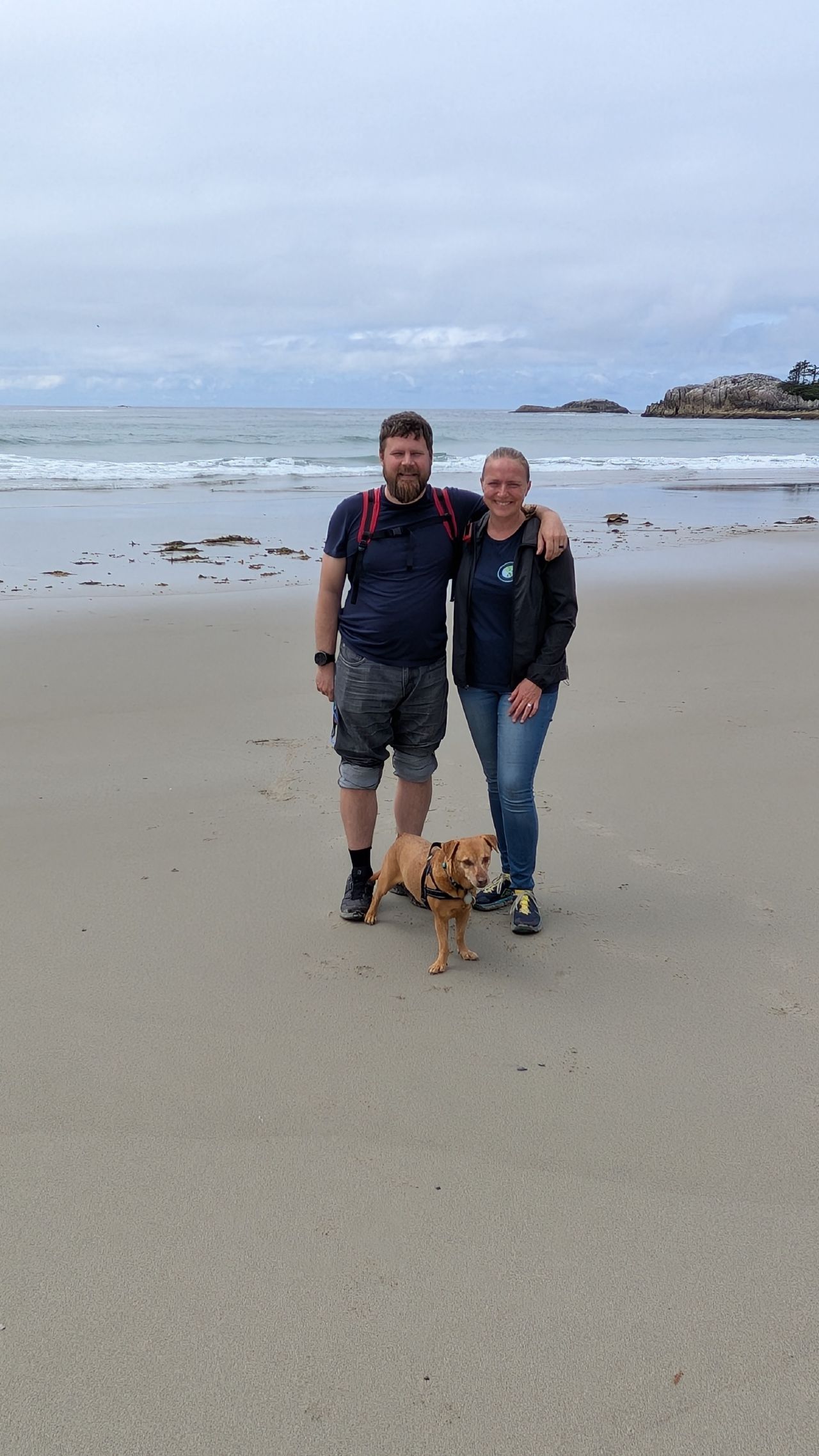 Brian, Rachel, and Maui standing together on the wide sandy beach at Pruth Bay