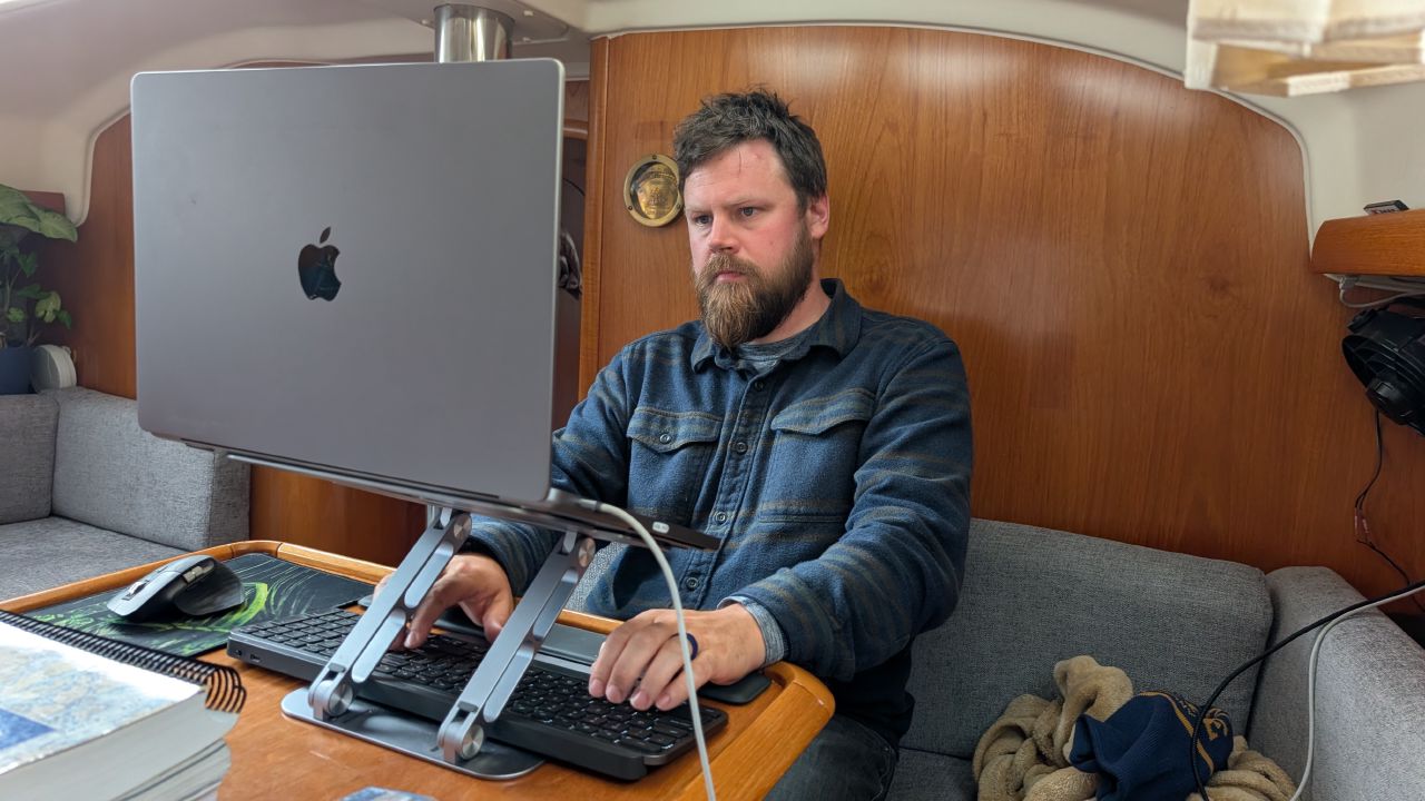 Brian working on his laptop at the nav station below deck on a rainy day at anchor