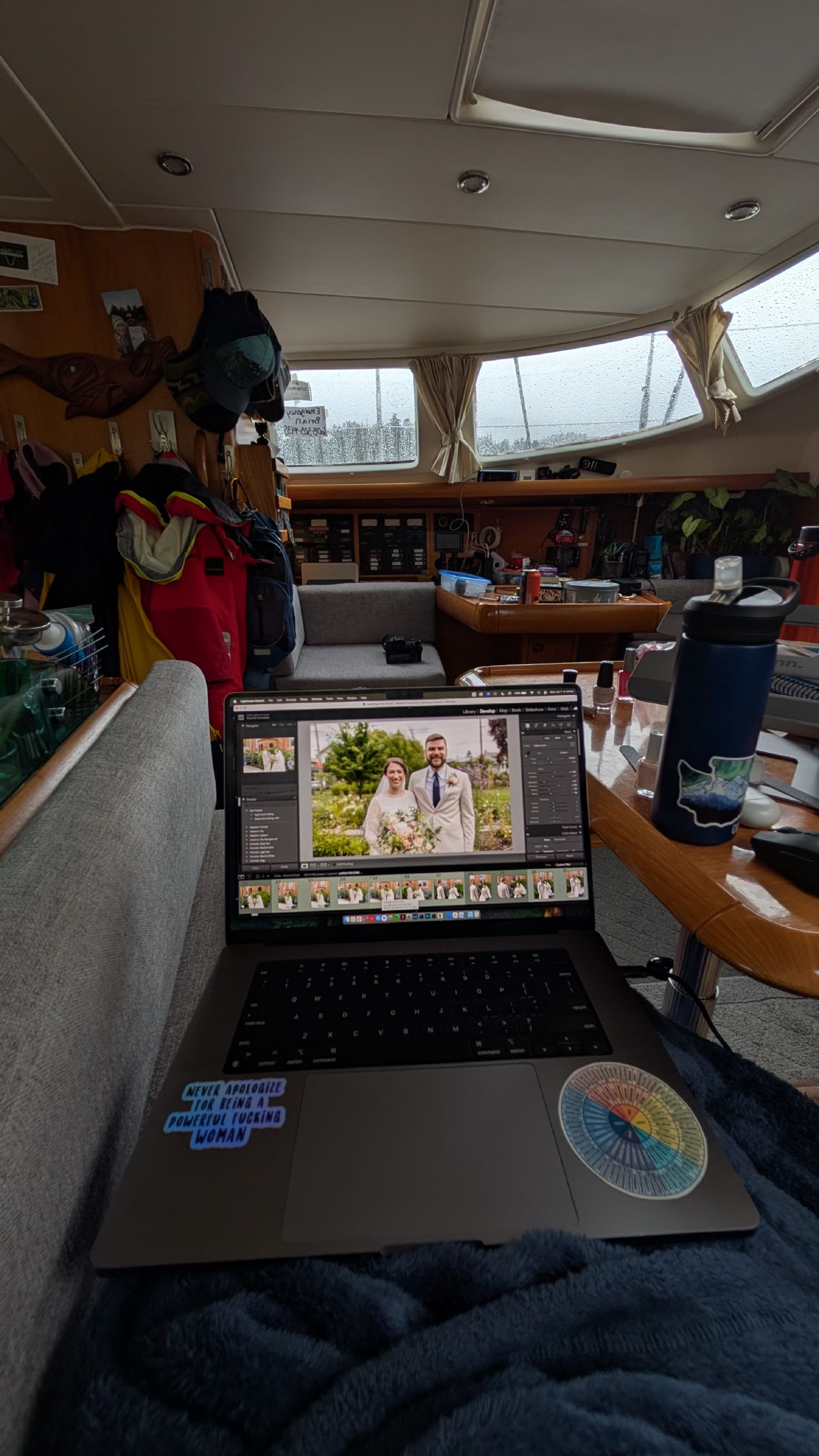 Rachel editing wedding photos on her laptop in the cozy cabin below deck on a rainy day