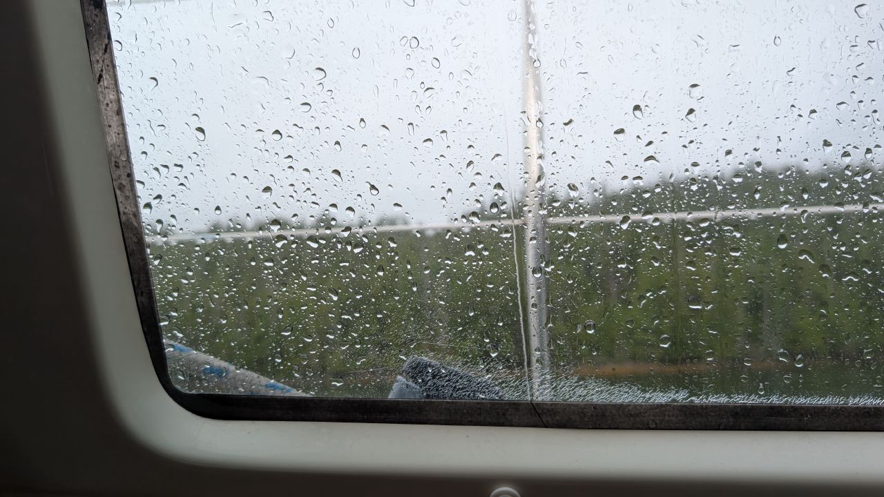 Raindrops covering the porthole window of the sailboat on a rainy day at Rock Inlet