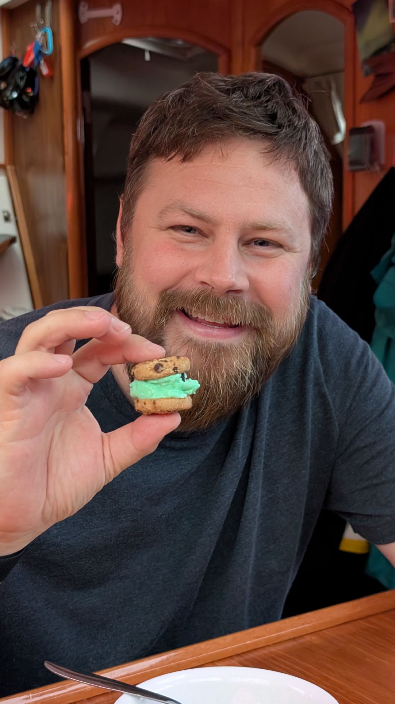 Brian smiling and holding a homemade mini mint ice cream sandwich below deck