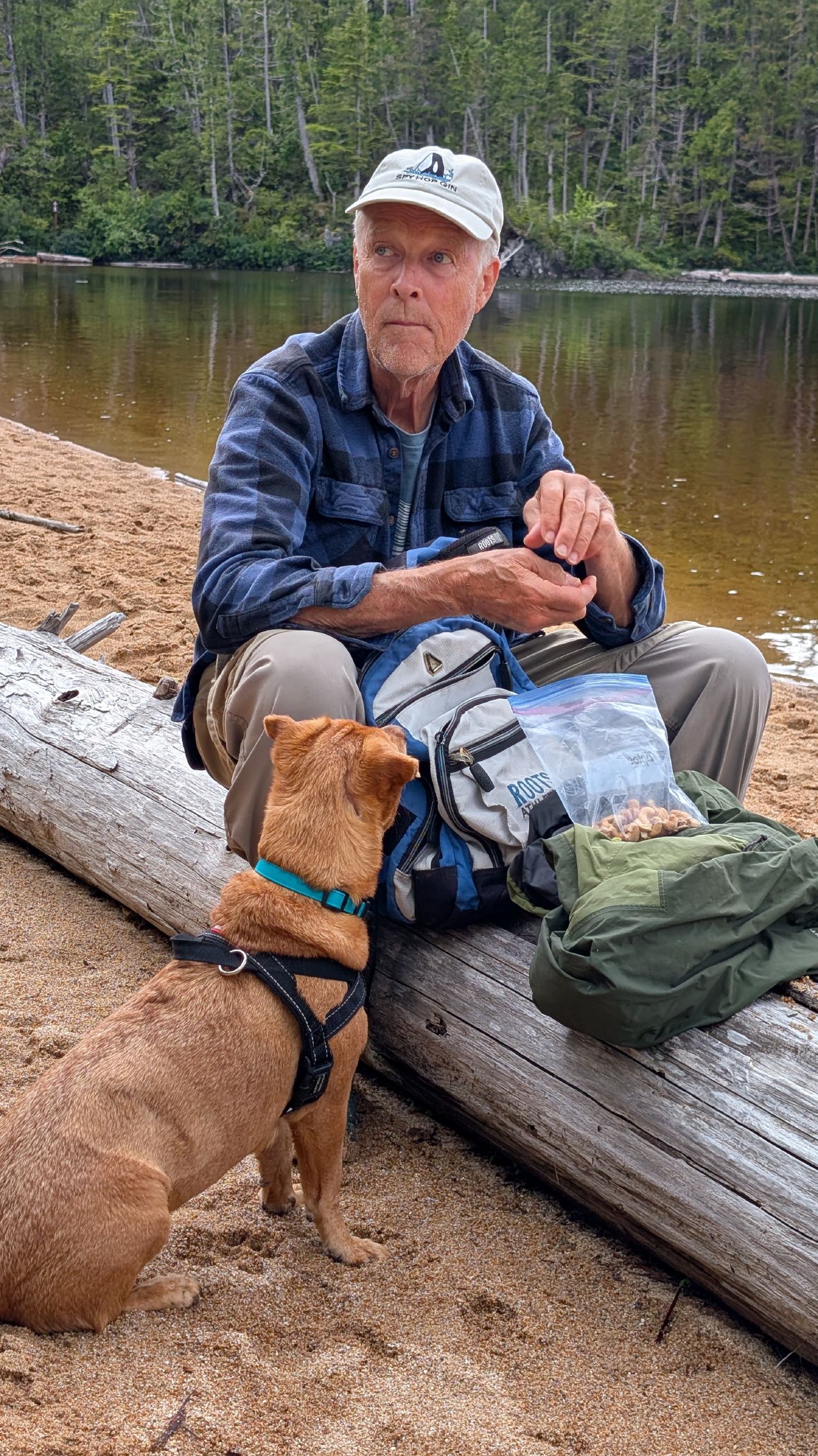 Maui and a fellow hiker taking a snack break on a log at the freshwater lake shore