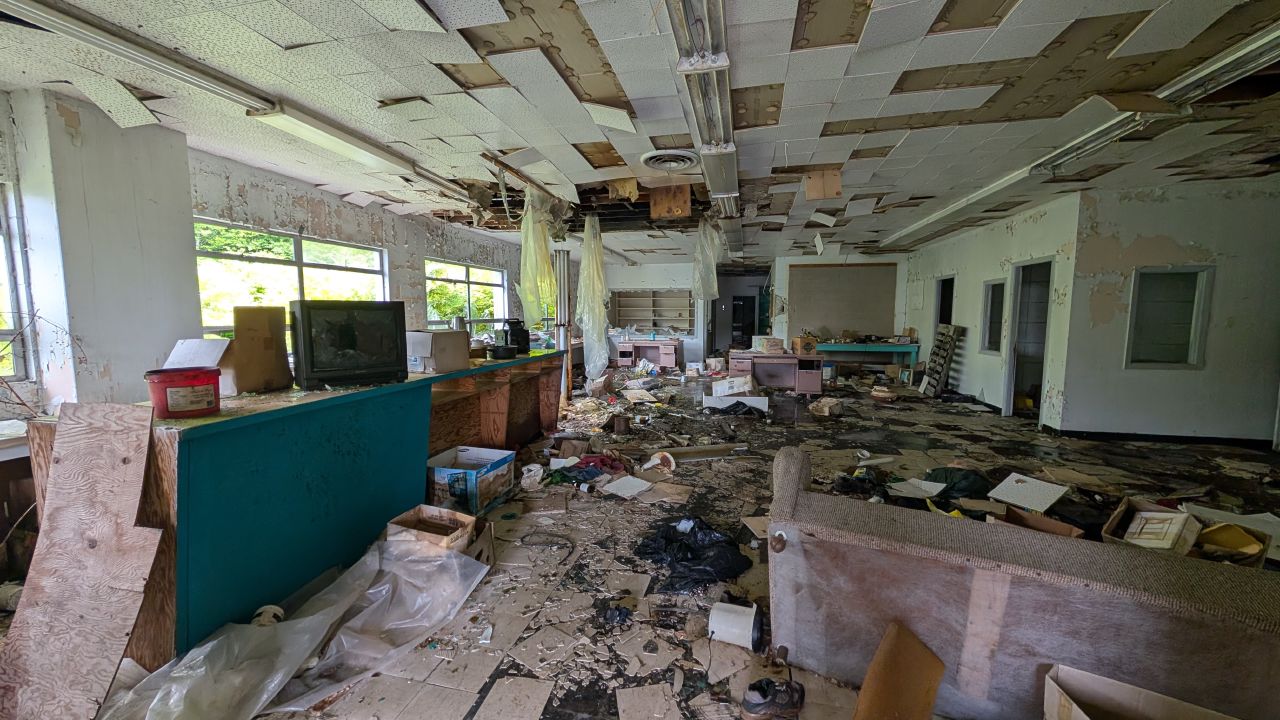 Abandoned recreation hall with old TV, pool table, and debris scattered everywhere in Namu