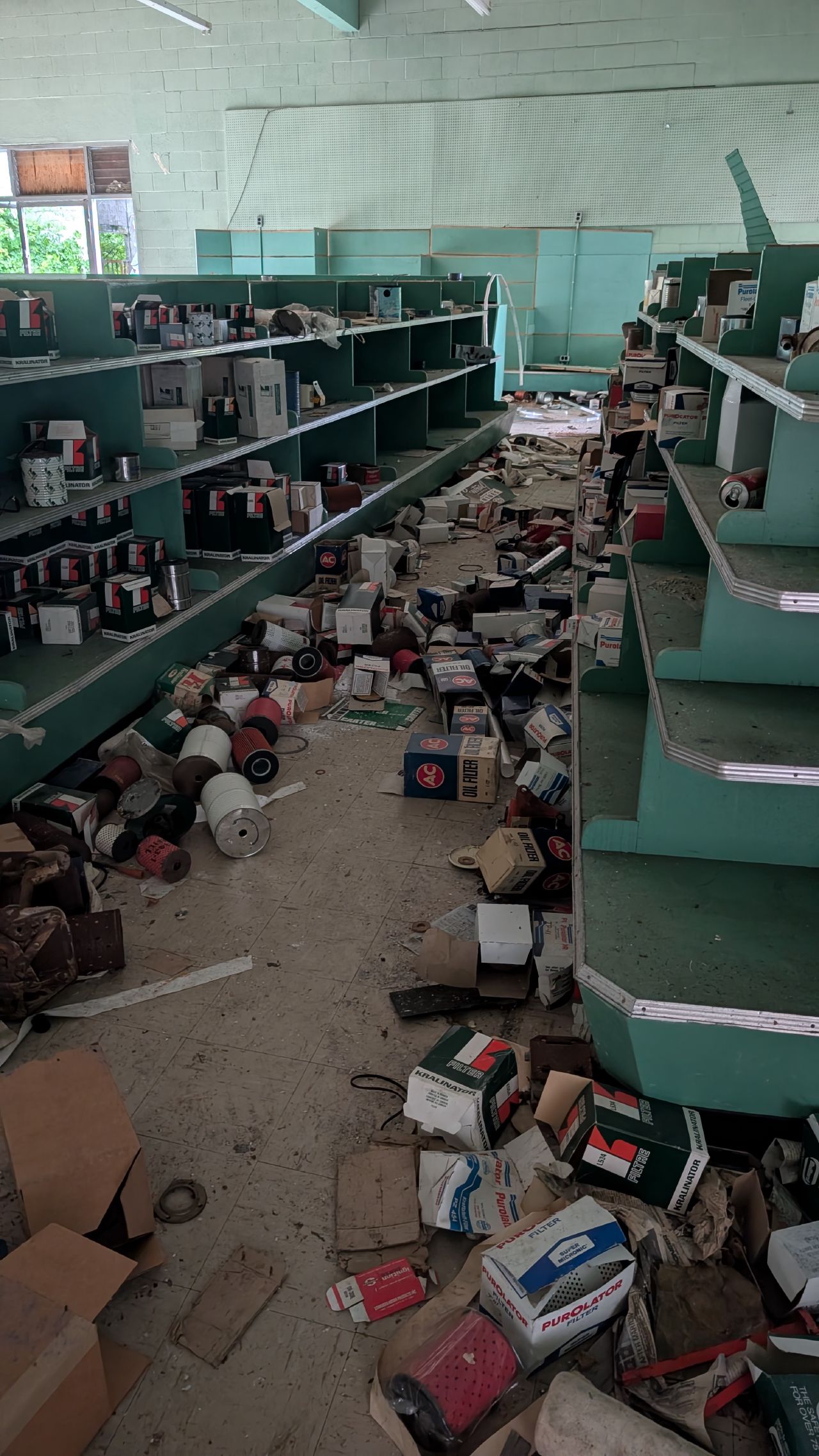 Abandoned store with green shelves and scattered oil filters and supplies in Namu