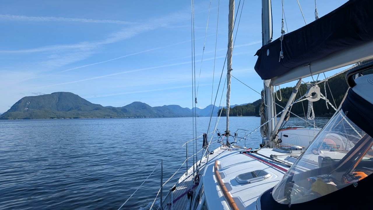View along the foredeck of SV Yahara with blue sky and mountains on the passage