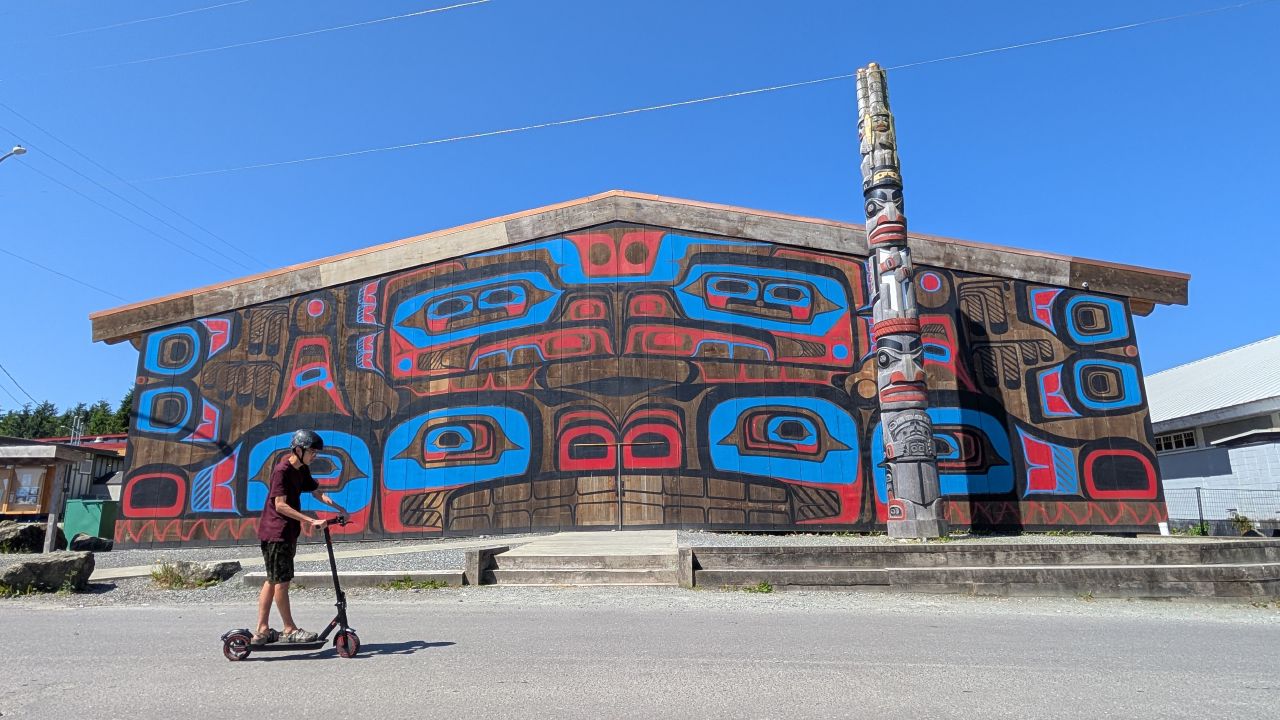 First Nations big house in Bella Bella with vibrant painted facade and totem pole out front