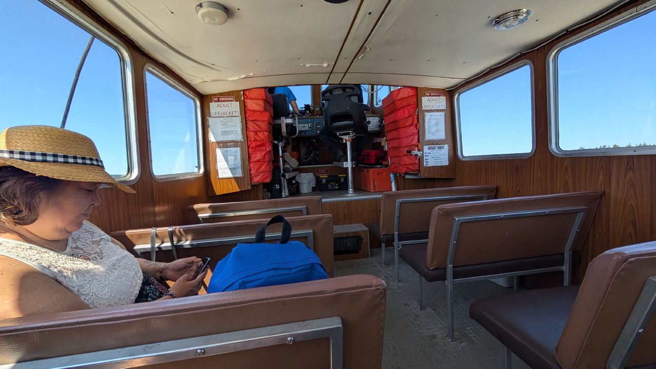 Rachel riding the water taxi from Shearwater to Bella Bella, checking her phone in the cabin