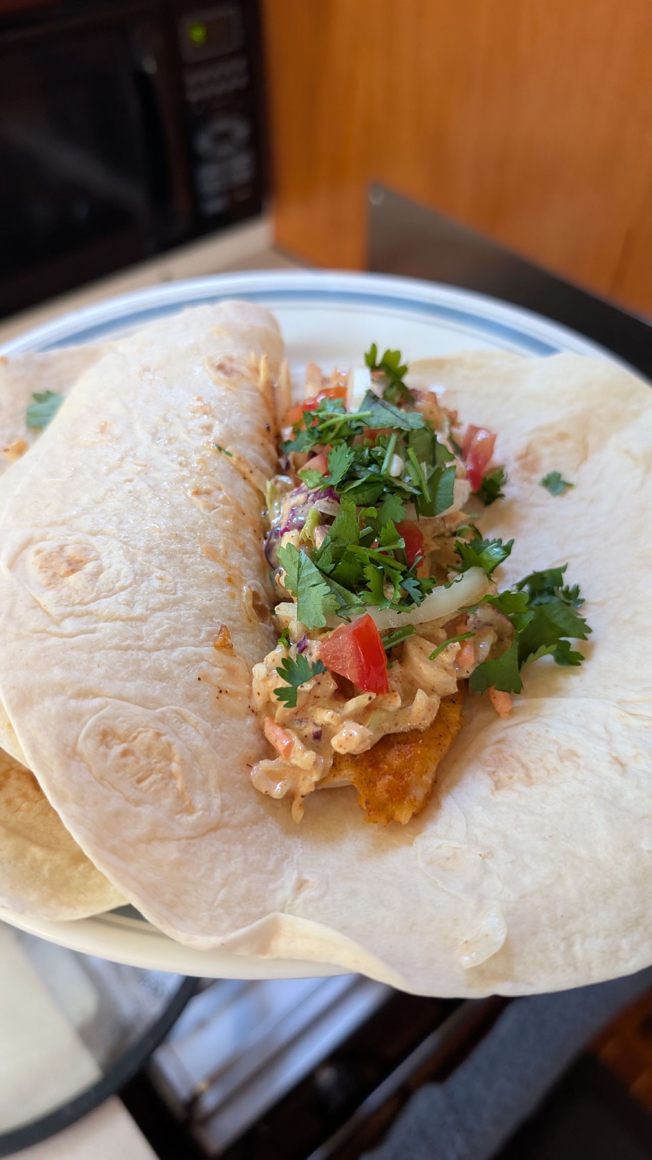 Homemade fish tacos topped with cilantro, slaw, and pico de gallo served in the boat galley