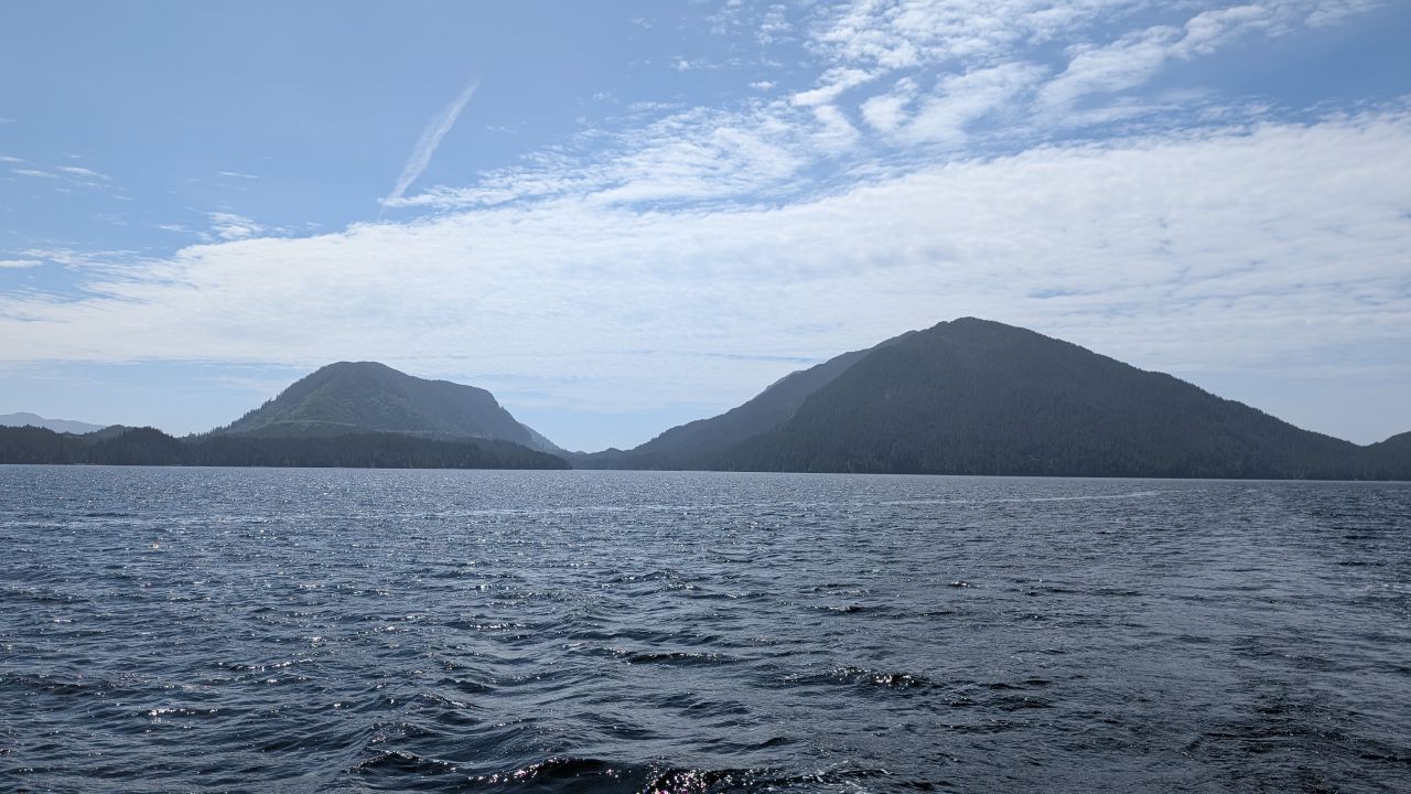 Forested mountains rising from the water on the sunny passage to Rescue Bay