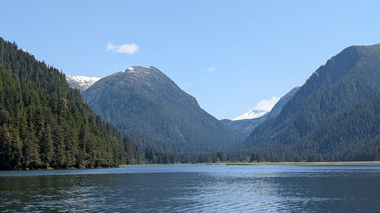 Snow-capped mountains towering over the calm waters of Khuntz Bay on a clear day