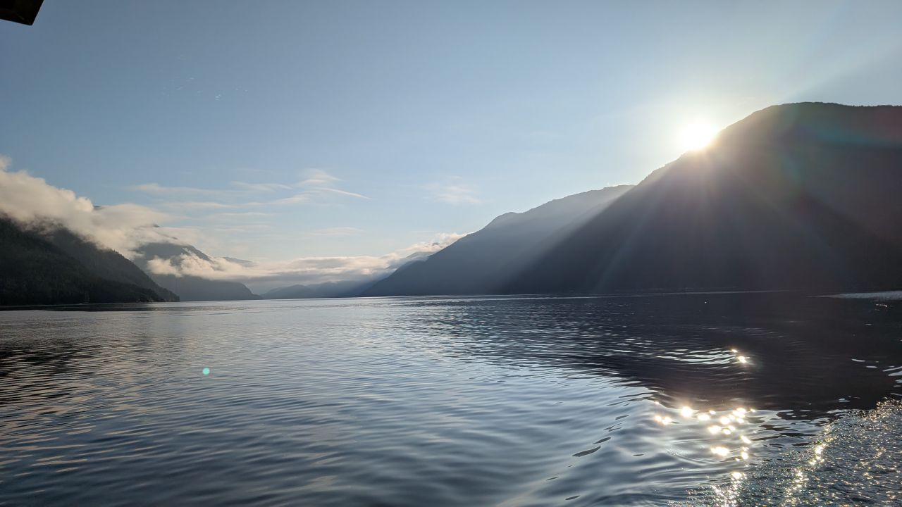 Sun rising over the mountains with light sparkling on the glassy water of the channel