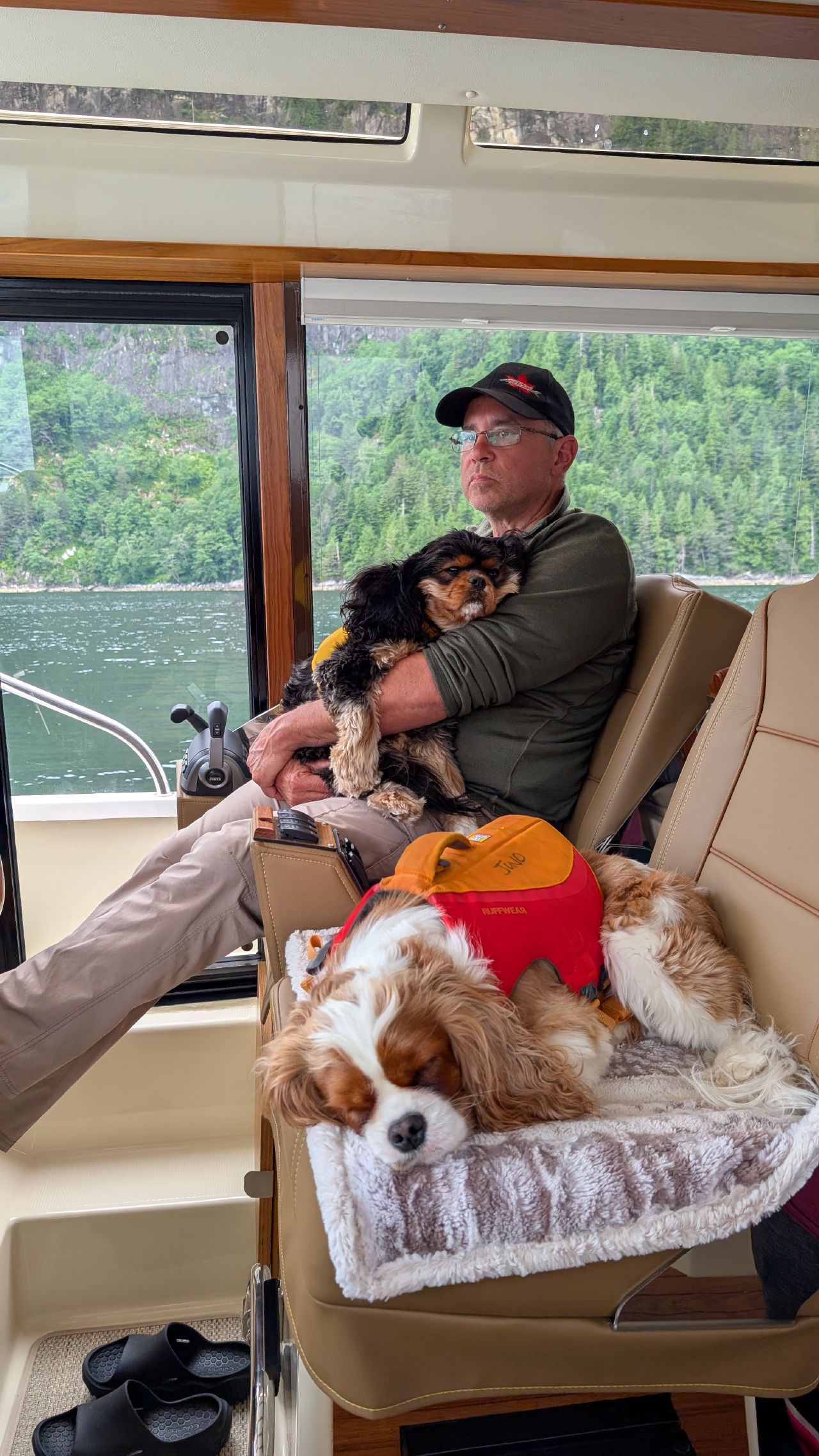 Friend sitting with two Cavalier King Charles Spaniels on the buddy boat pilothouse