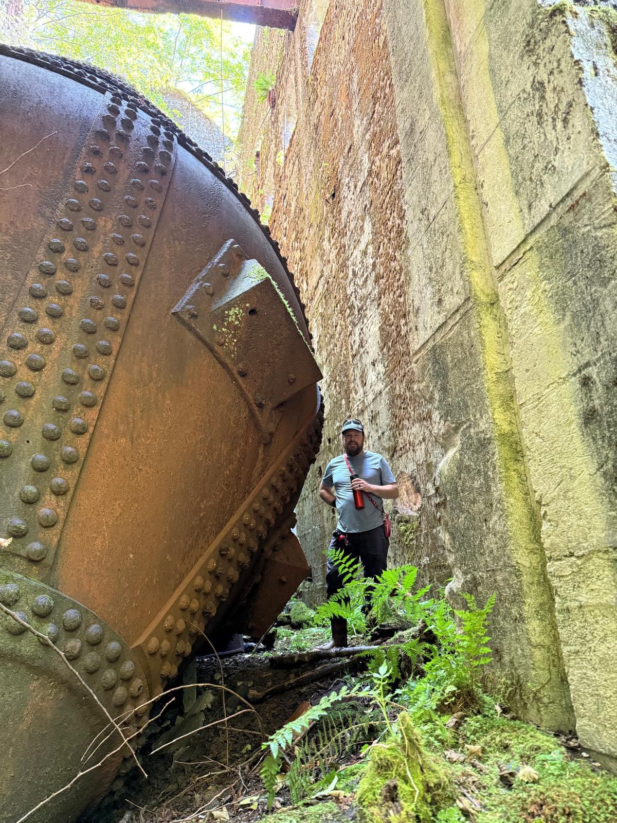 Brian standing next to a massive rusted industrial boiler at the Swanson Bay ruins