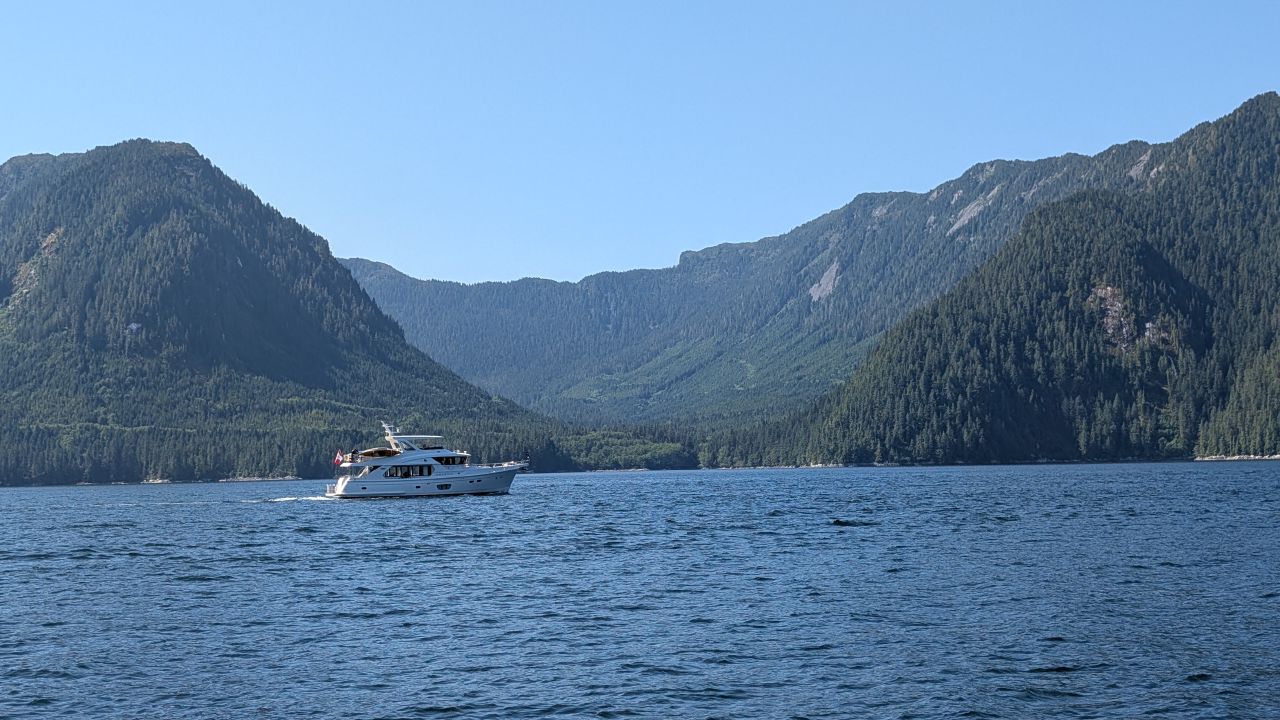 Motor yacht cruising past dramatic snow-capped mountains during the passage north