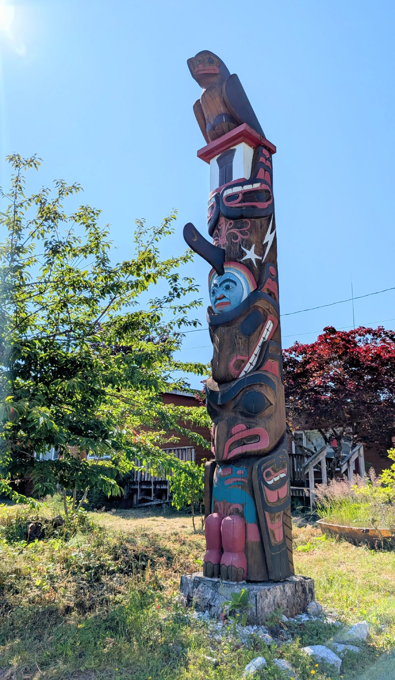 Colorful First Nations totem pole standing in Hartley Bay on a sunny day