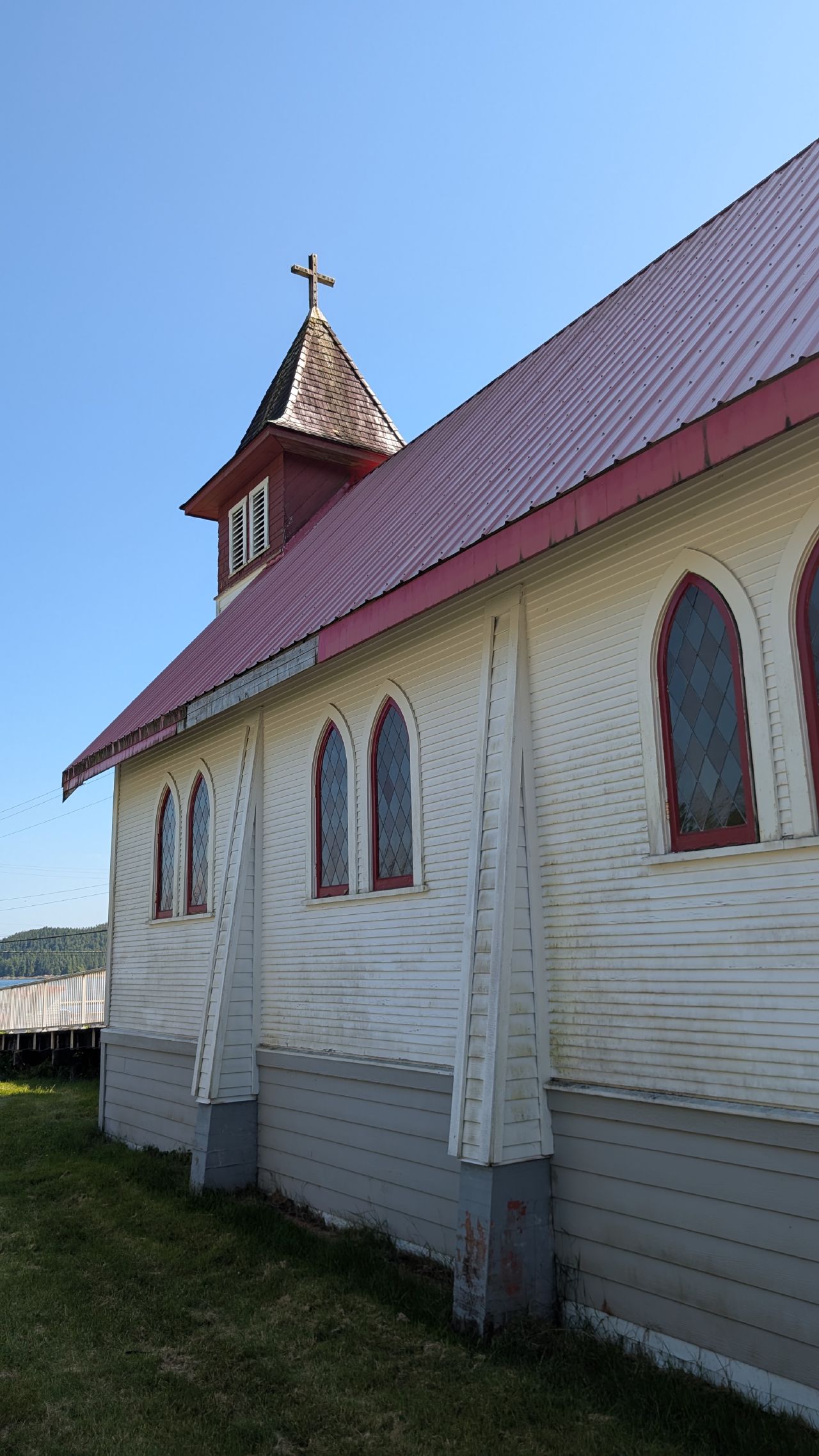 White church with a red metal roof and steeple in Hartley Bay