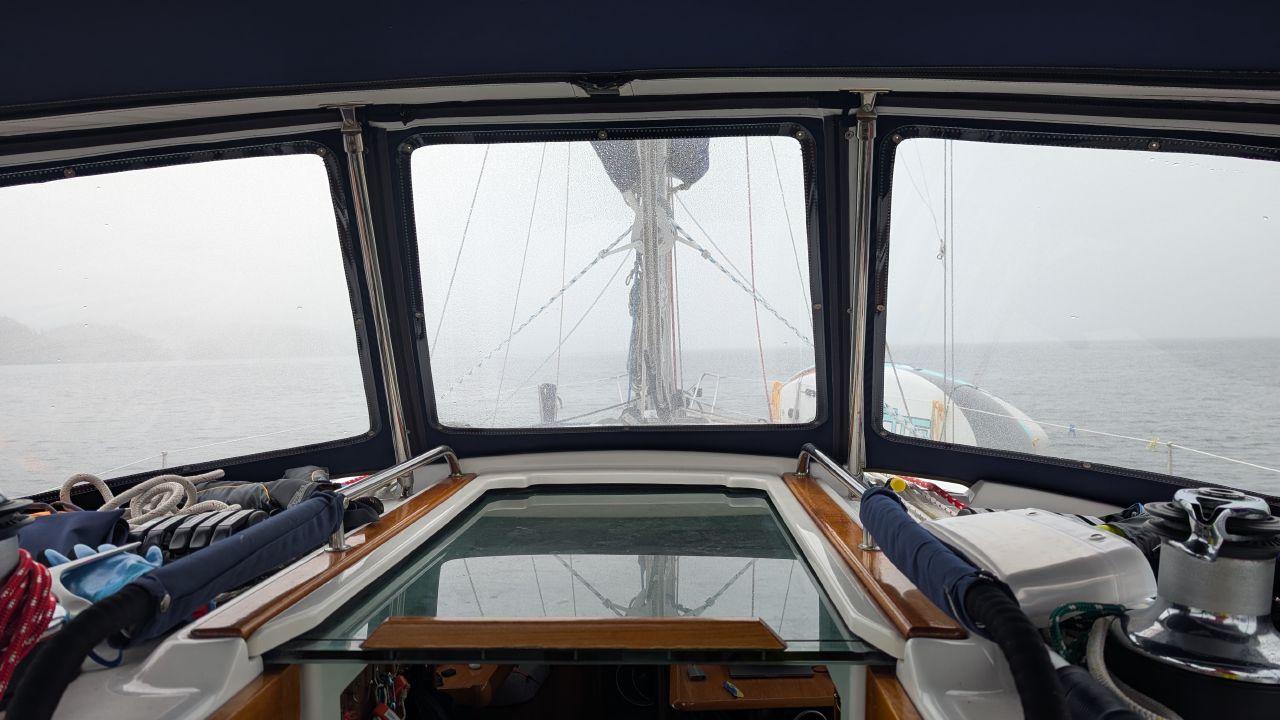 Foggy view forward through the rain-splattered dodger windows during the passage