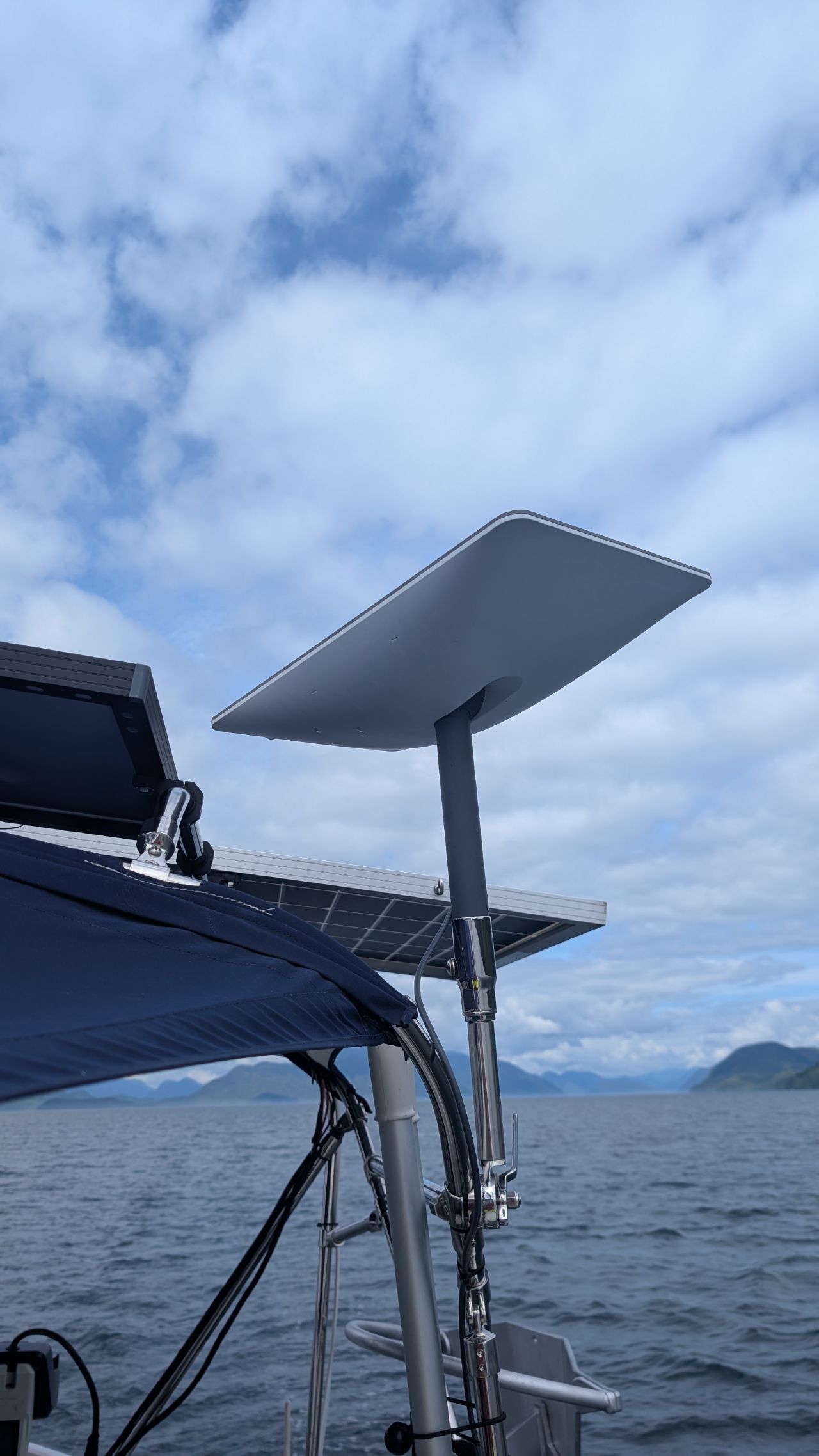 Starlink satellite dish mounted on the sailboat arch with mountains and clouds in the background