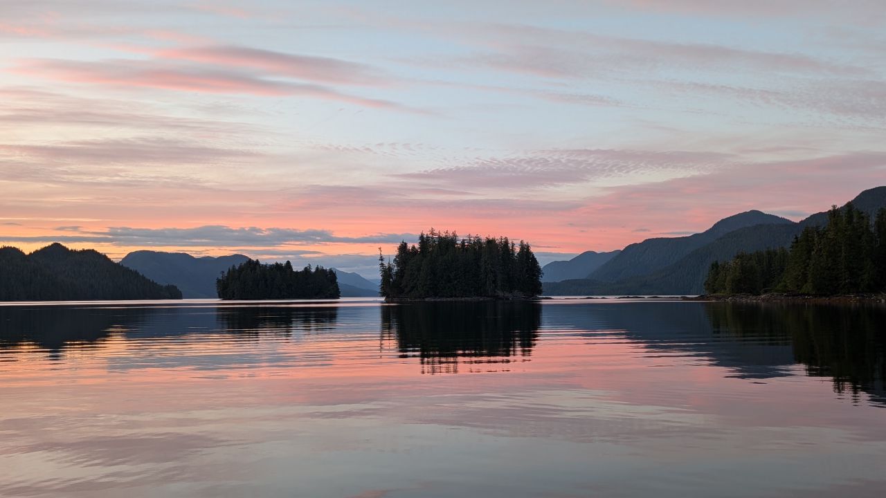 Stunning pink sunset reflecting on glassy water with forested islands at Rescue Bay