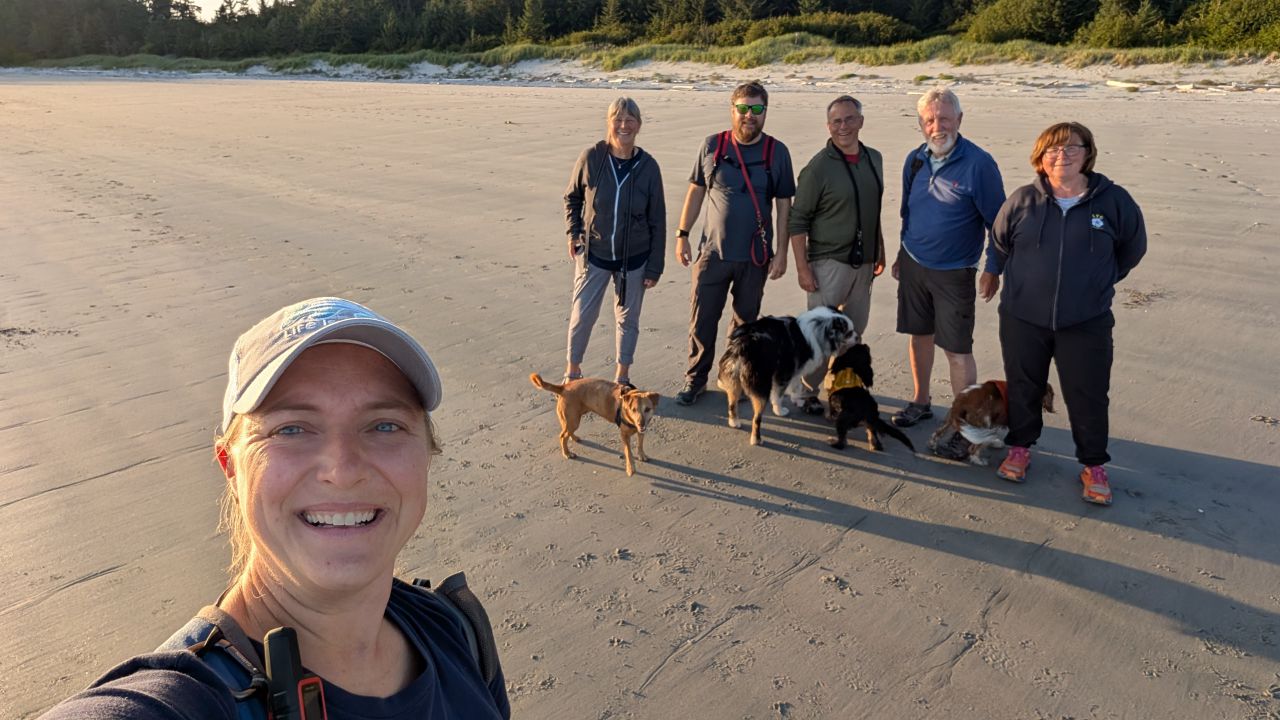 Rachel taking a group selfie with the flotilla crew and their dogs on North Beach at Pruth Bay