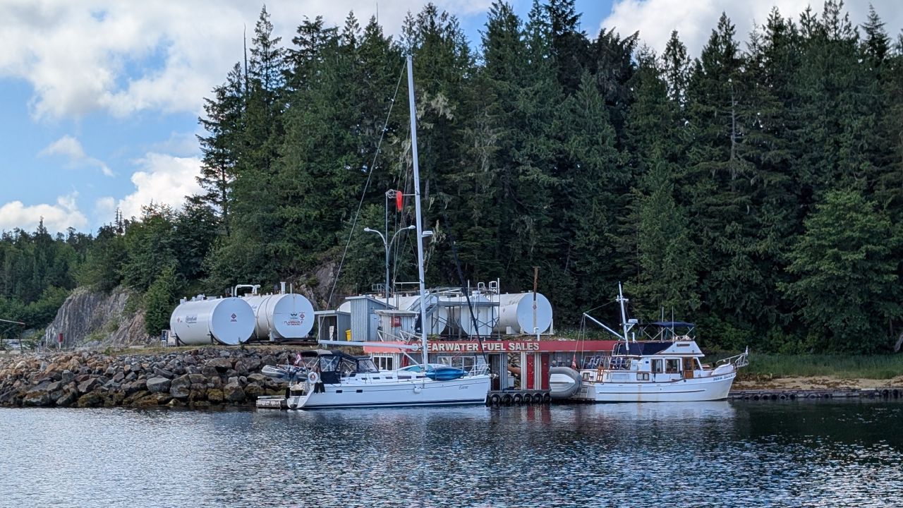 SV Yahara tied up at the Shearwater fuel dock with large fuel storage tanks behind