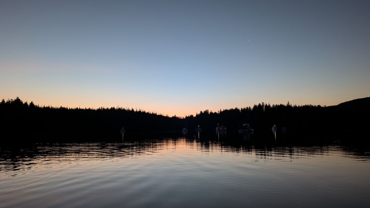 Predawn silhouette of boats anchored in Fury Cove with the first hint of sunrise on the horizon