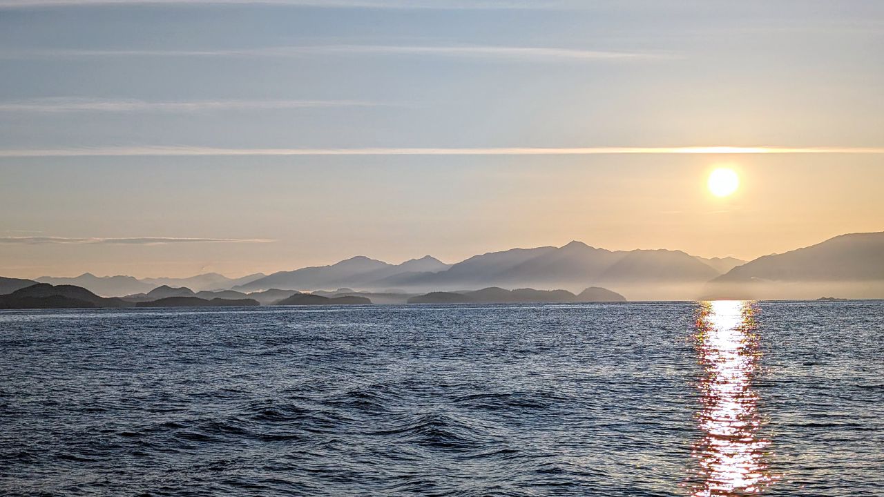Sunrise over layered misty mountains as SV Yahara leaves the Central Coast heading south around Cape Caution
