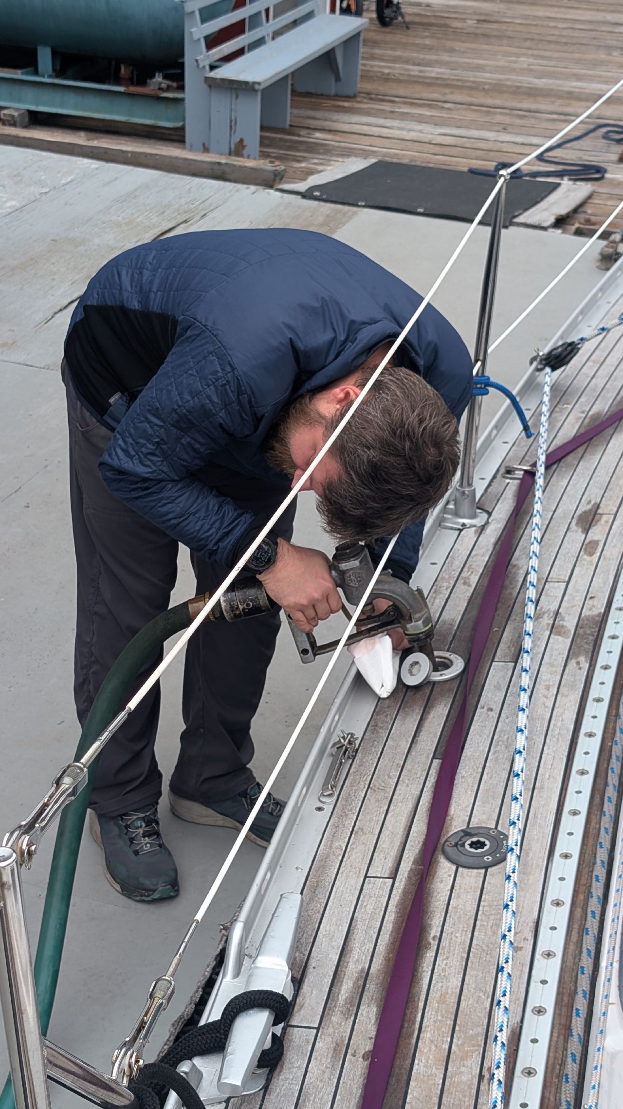 Brian bending down to connect the diesel fuel hose on the deck of SV Yahara at Sullivan Bay