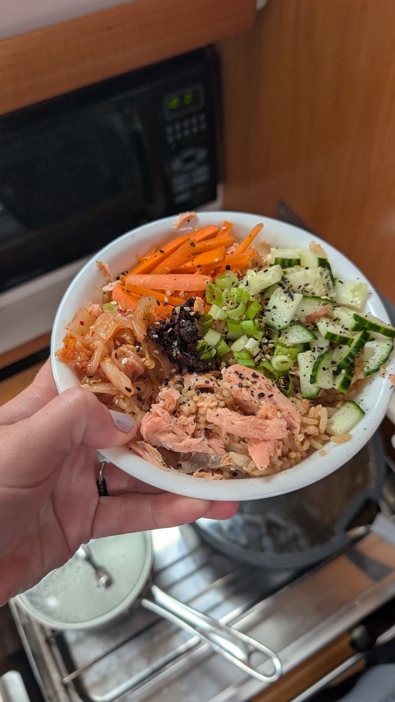 A salmon Asian rice bowl with kimchi, carrots, cucumber and sesame seeds made in the galley
