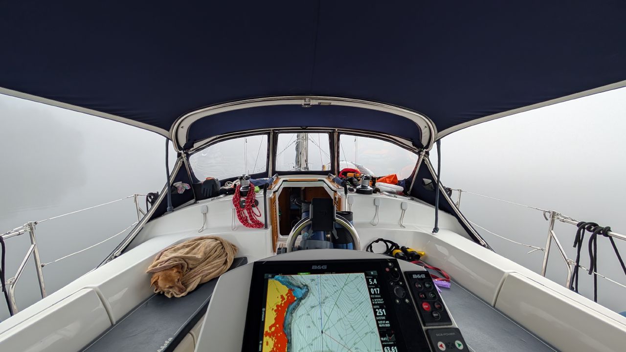 View from the cockpit of SV Yahara with the chartplotter lit up navigating through thick fog