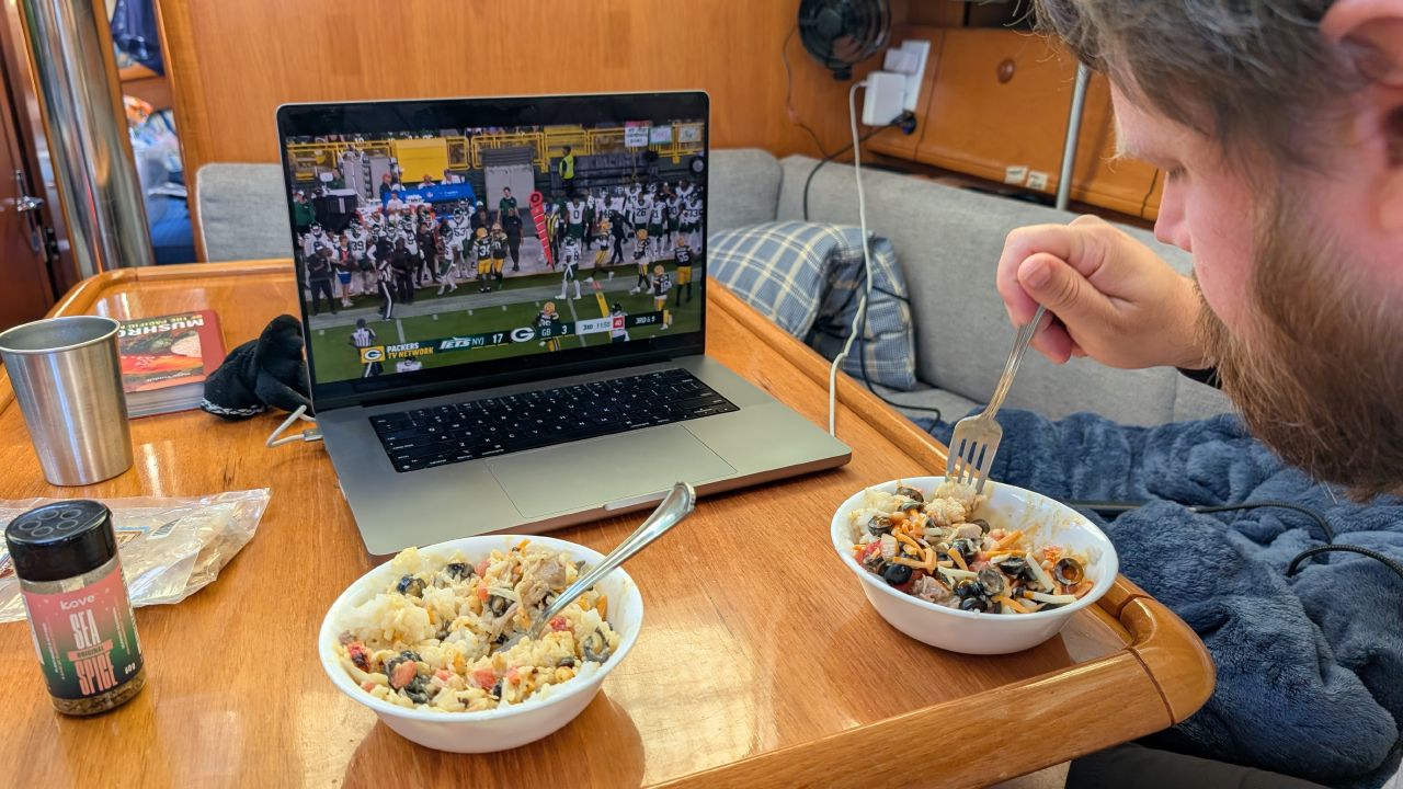 Brian eating dinner below deck while streaming the Packers preseason game on his laptop