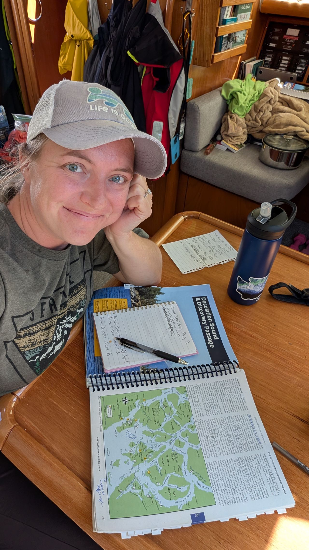 Rachel smiling while planning the route home with a Desolation Sound cruising guide and notebook