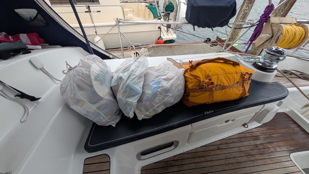 Three bags of garbage and recycling plus a duffel bag lined up on the cockpit seat ready to go ashore