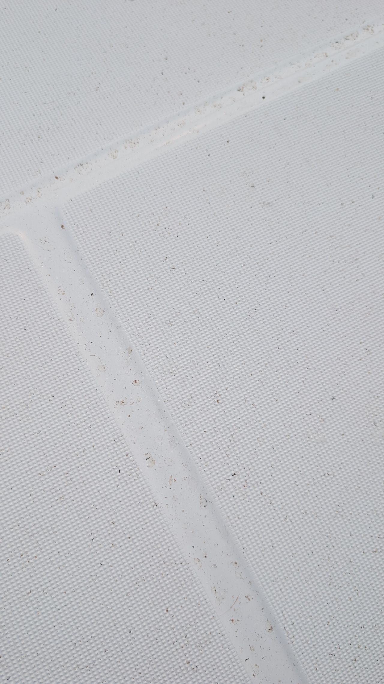 Close-up of wildfire ash particles settled on the white sail cover of SV Yahara
