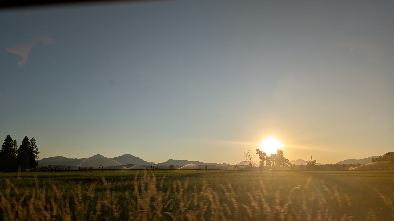 Golden sunset over farmland with irrigation sprinklers and mountains silhouetted in the distance near Ladysmith