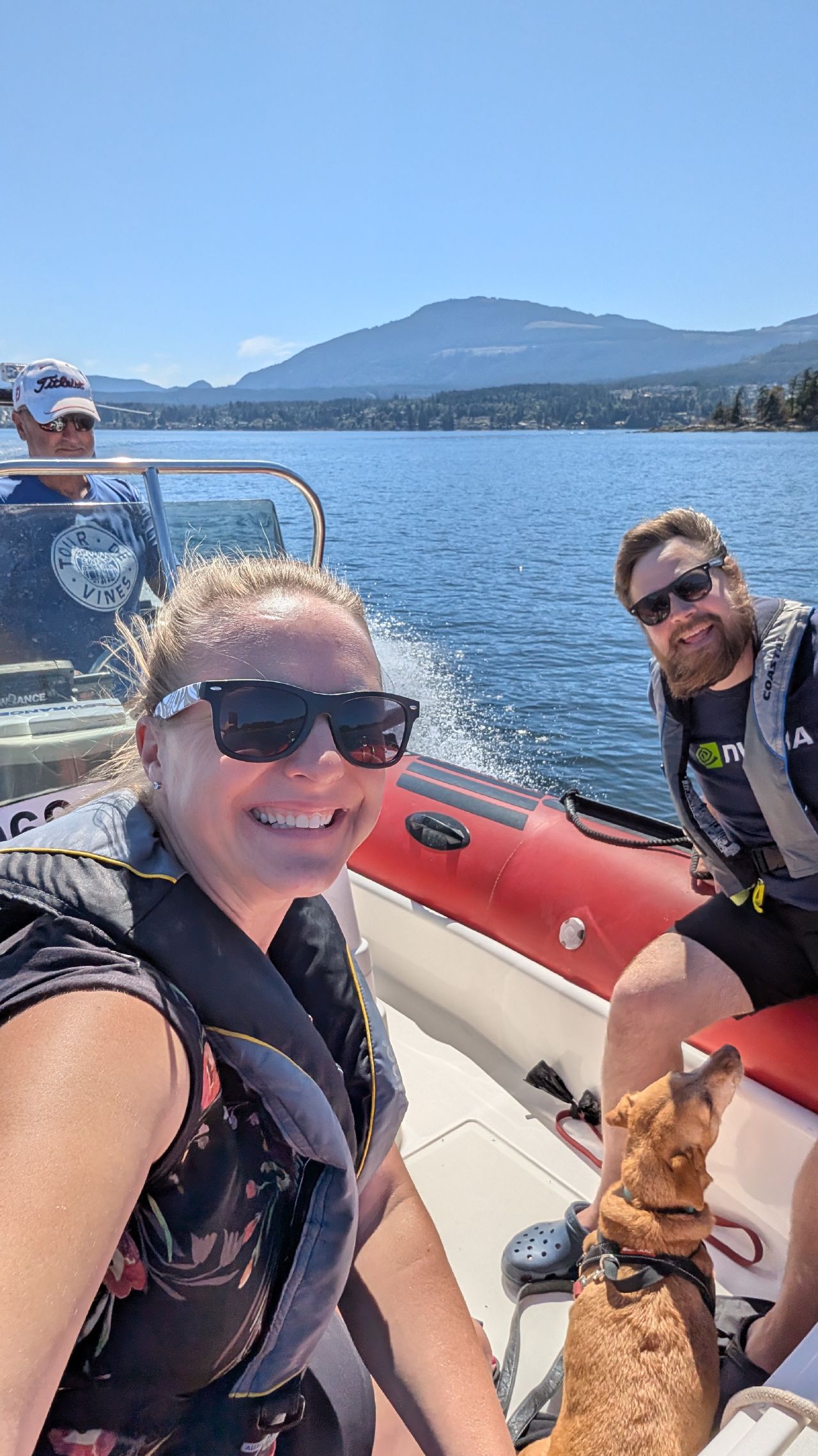 Rachel, Brian, and Maui riding in a friend’s zodiac across Ladysmith Harbour with mountains in the background
