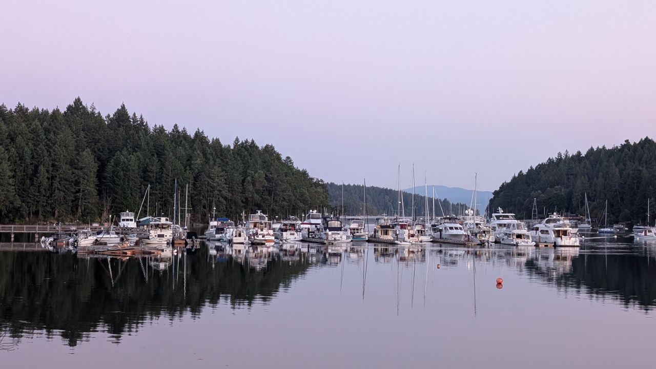 Boats lined up at the marina reflected in the calm glassy water of Telegraph Harbour at twilight