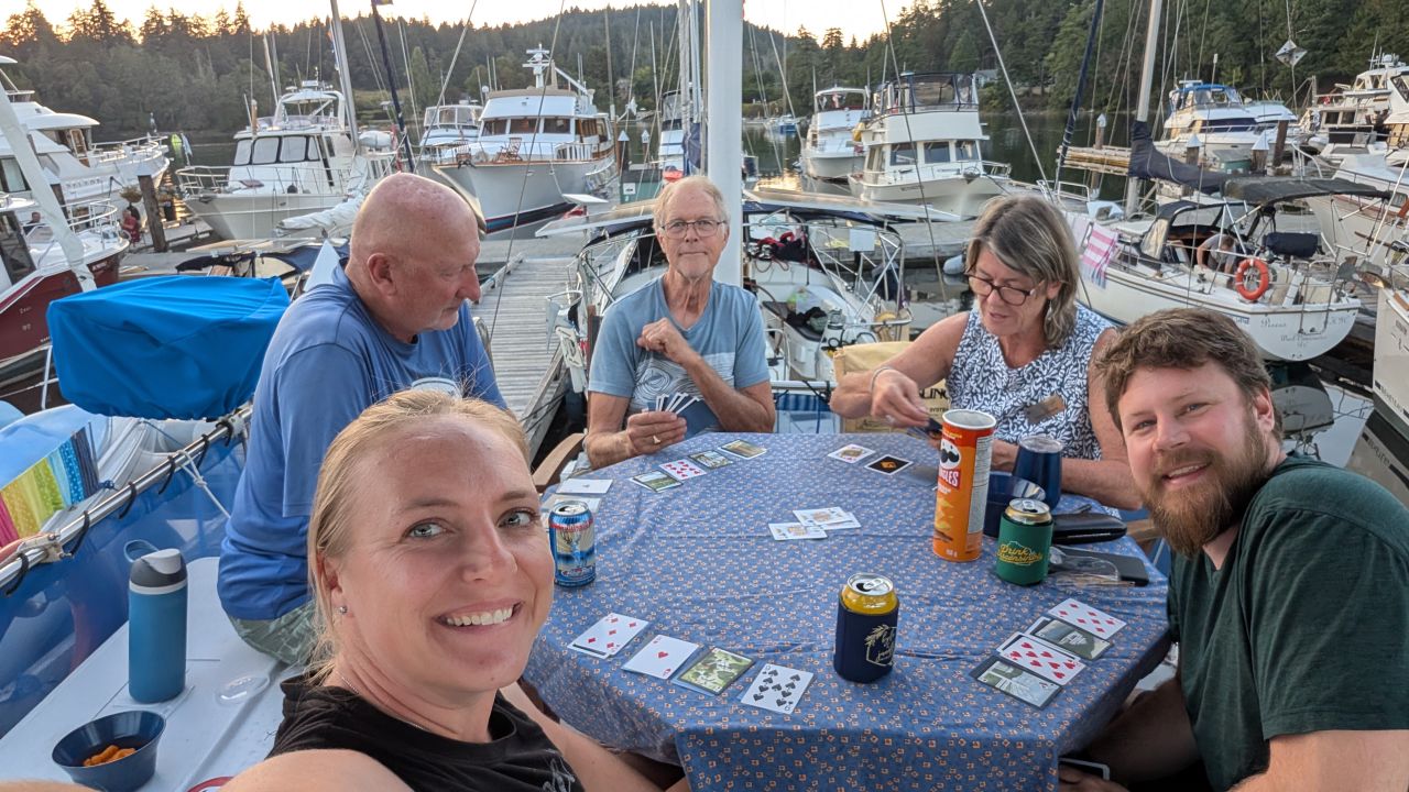 Rachel, Brian, and friends playing cards in the cockpit of a boat at Telegraph Harbour marina at dusk