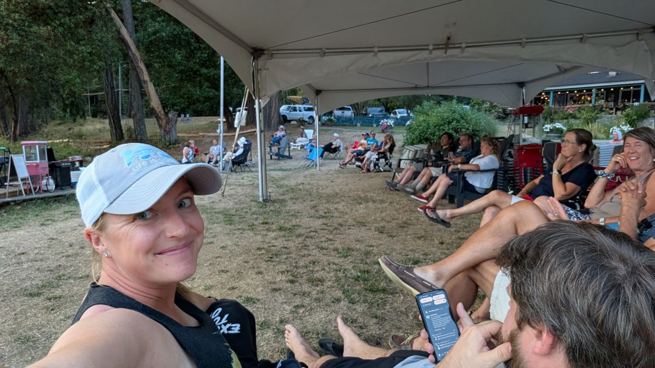 Rachel taking a selfie under the tent while cruisers enjoy live music at the rendezvous social