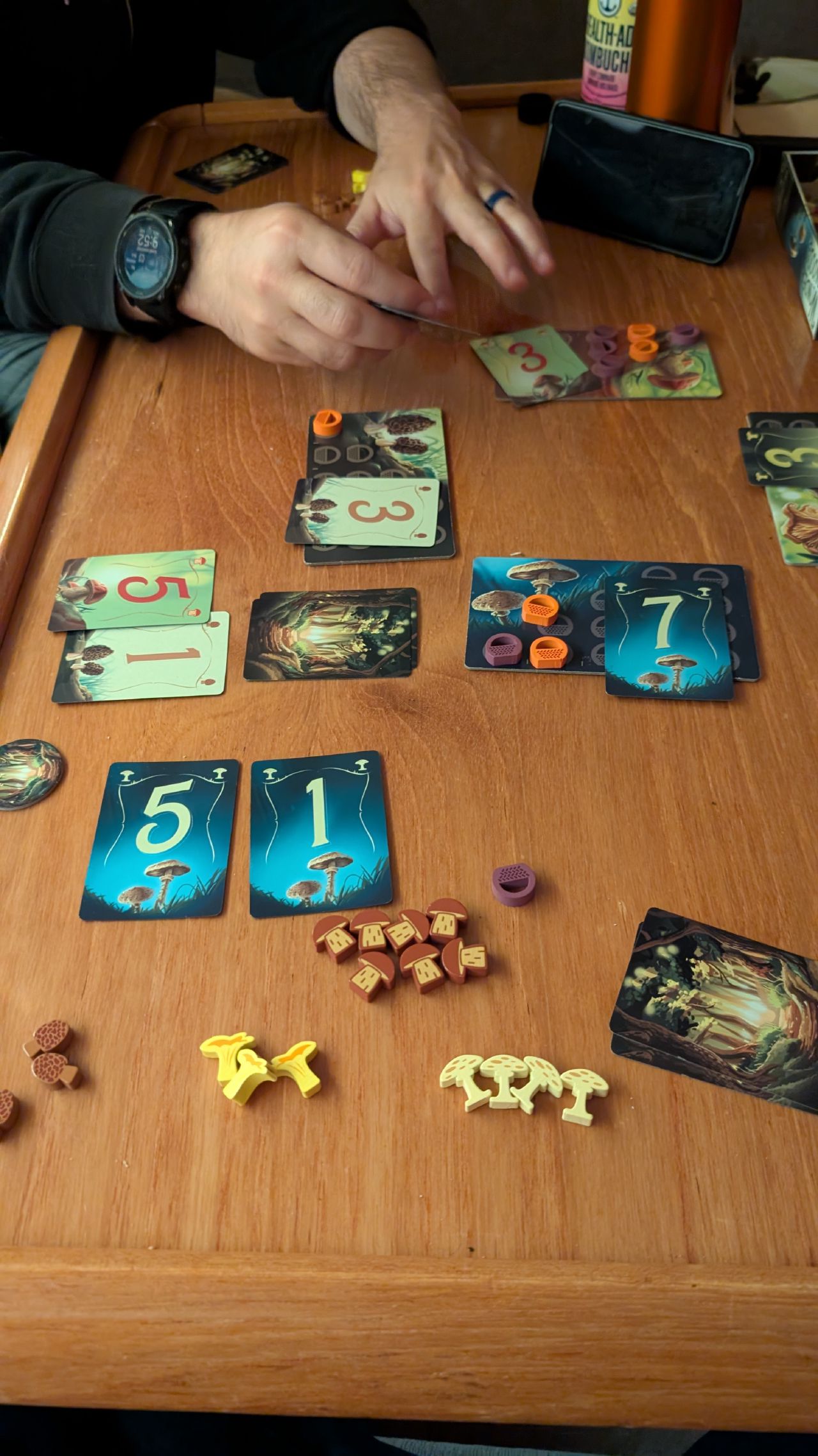 Playing a mushroom foraging themed board game with colorful cards and tokens on the boat