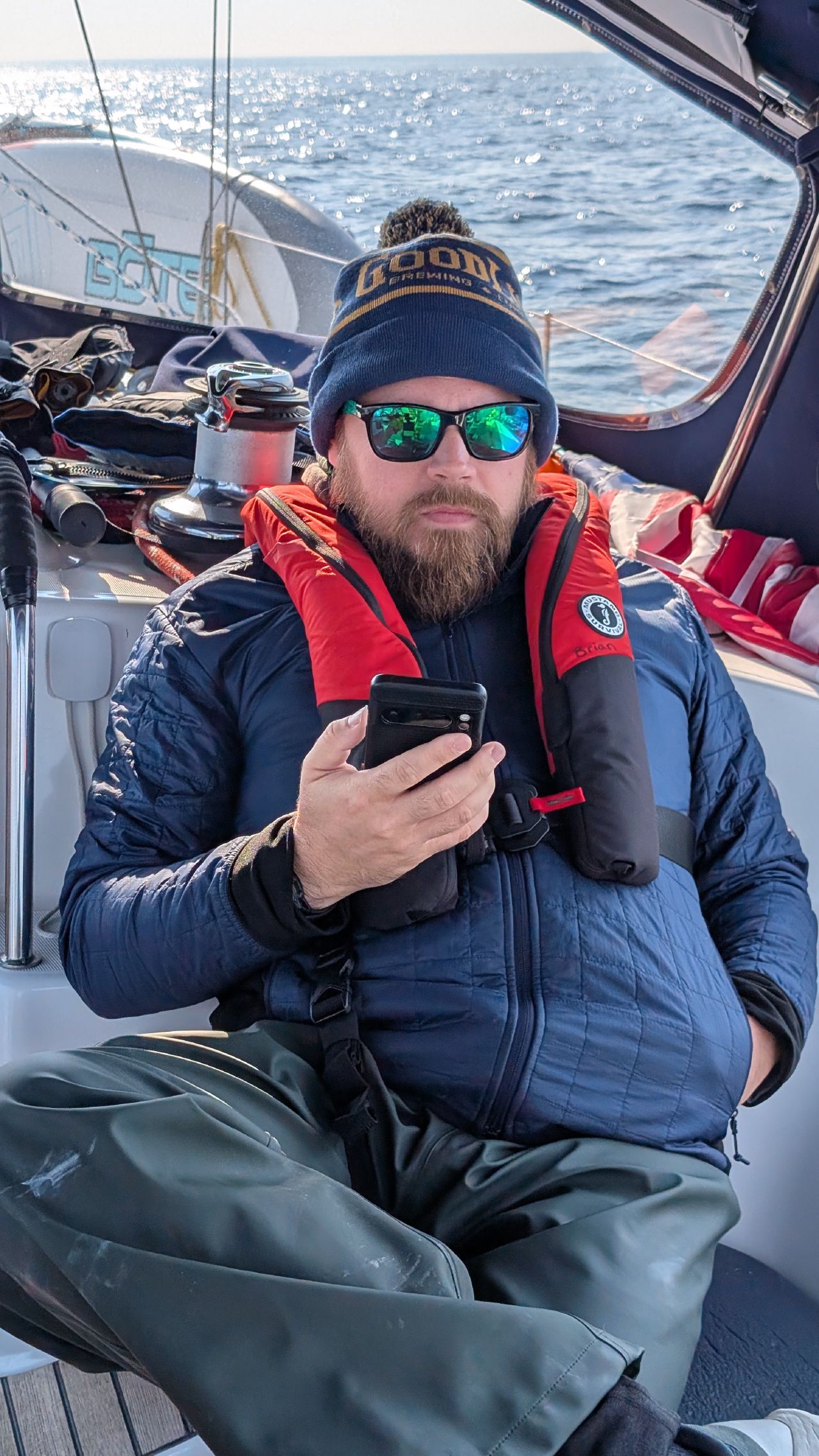 Brian bundled up in foul weather gear and life jacket calling US customs on his phone in the cockpit