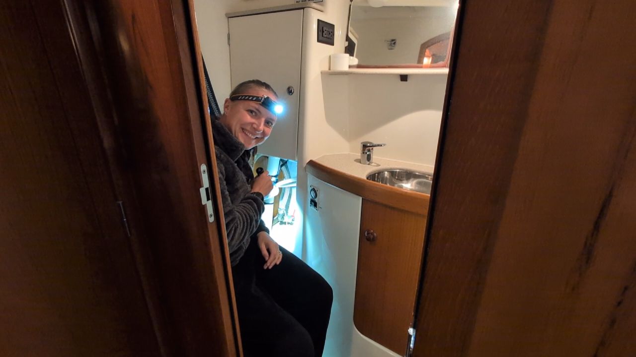 Rachel wearing a headlamp and smiling in the head compartment while checking for leaks